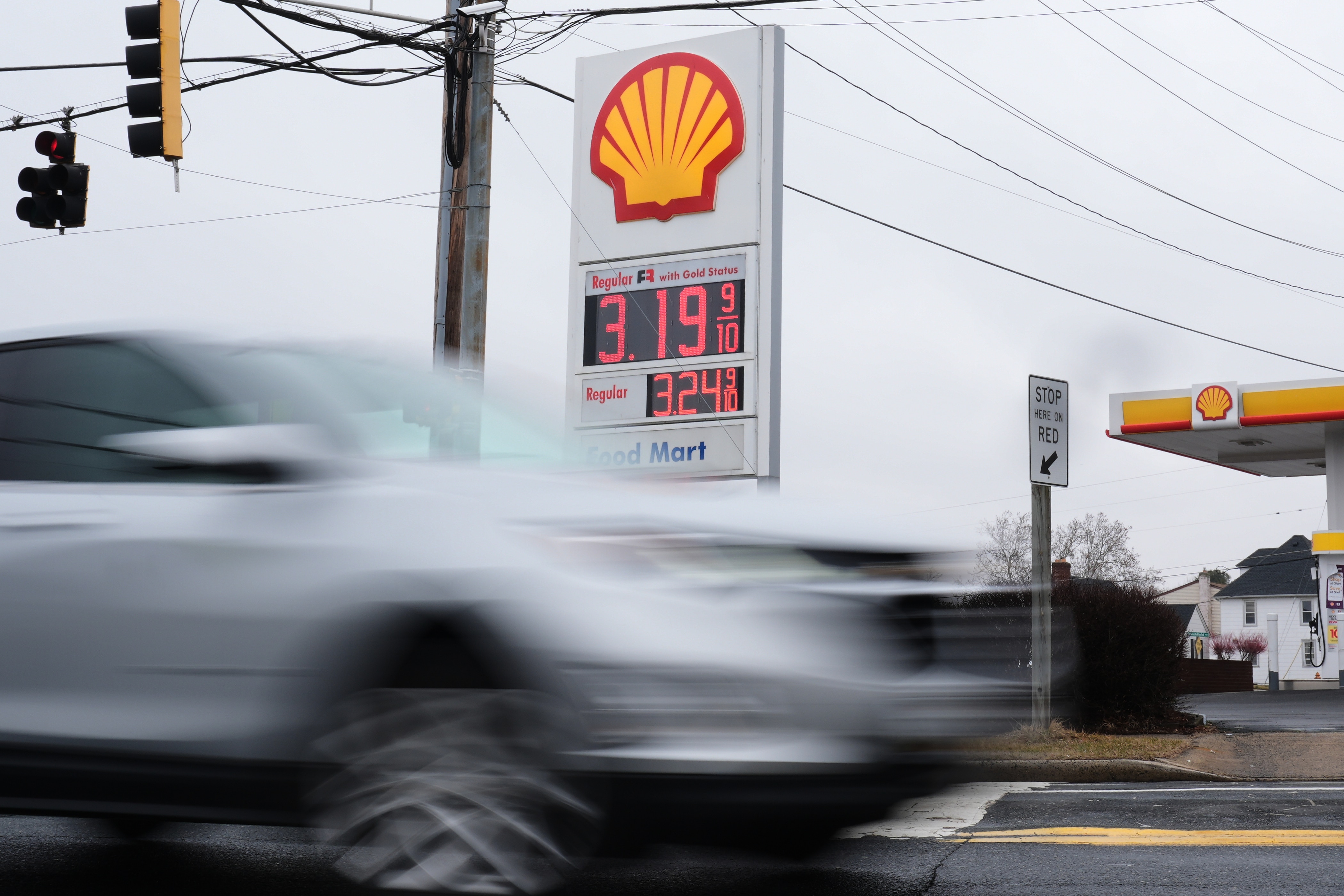 Fuel prices are displayed at a gas station as cars drive by in Baltimore.