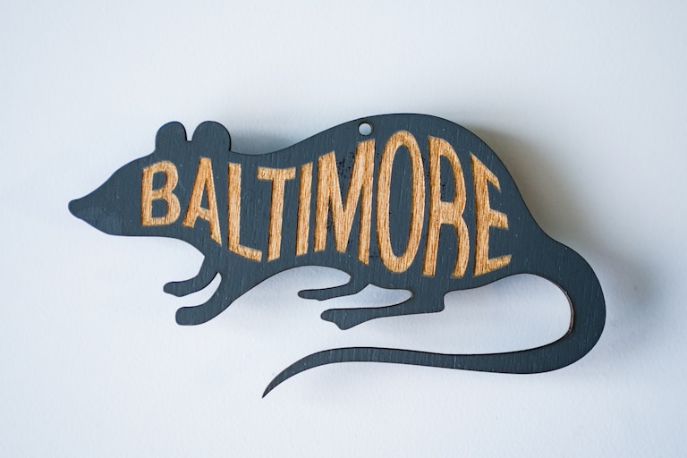 A wooden magnet showcasing Baltimore's connection to rats.