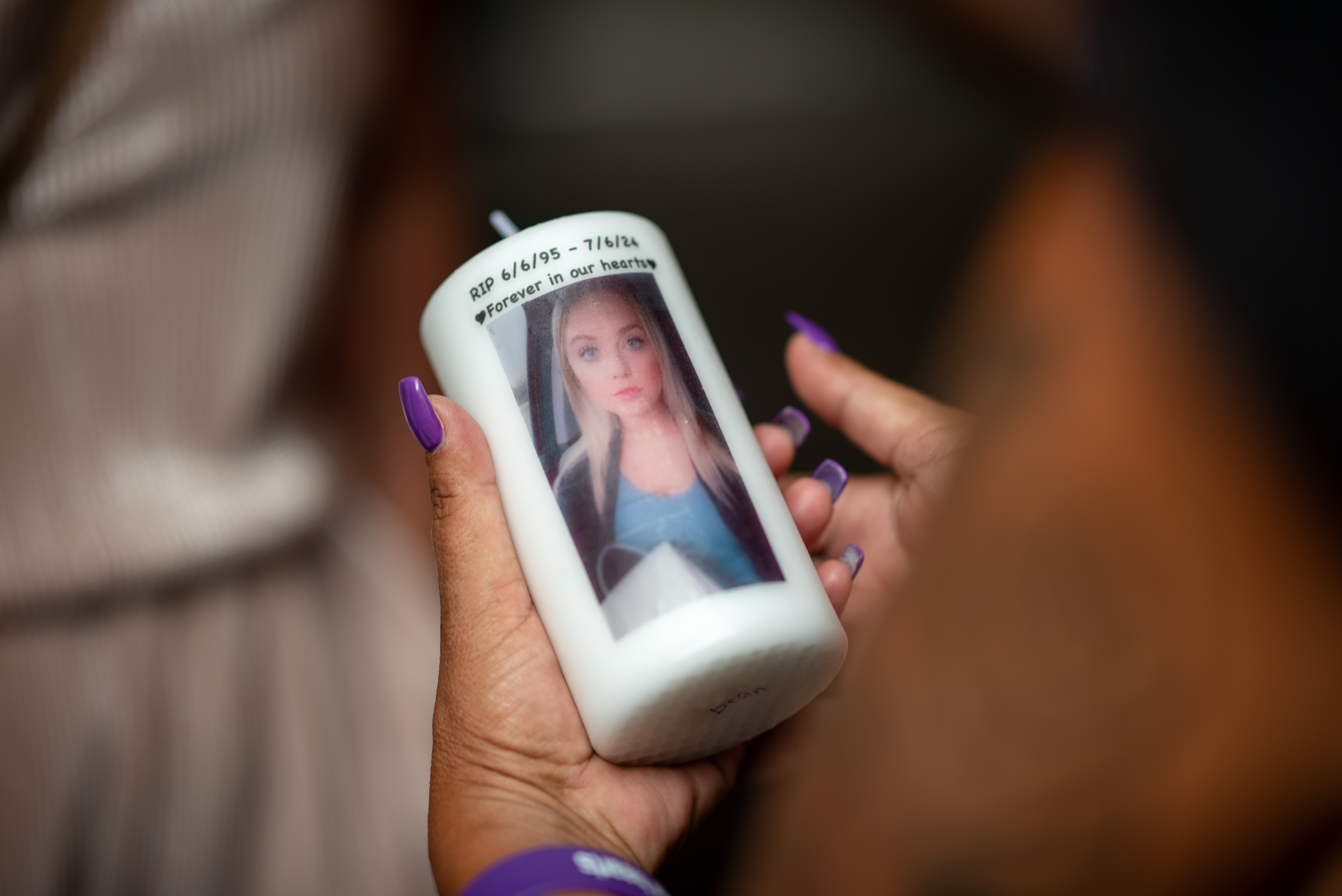 A family friend holds a candle with Autumn Harvey's face on it during a vigil held in her honor on July 14, 2024.