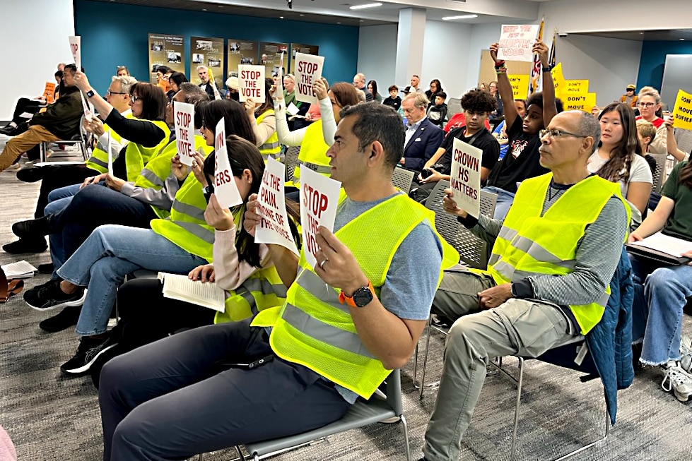 Montgomery County parents, including Nihar Shah, center, hold signs at Thursday's school board meeting, urging members not to use Crown High as a temporary holding campus.