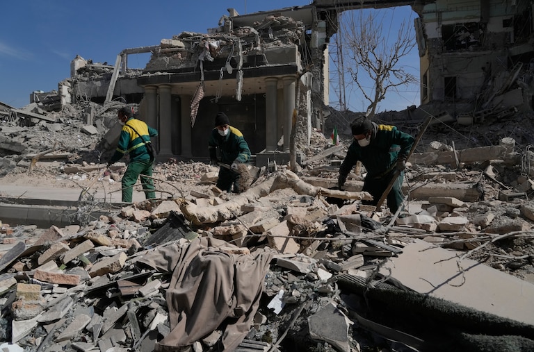 Workers remove the rubble of a police facility struck during the U.S.–Israeli military campaign in Tehran.
