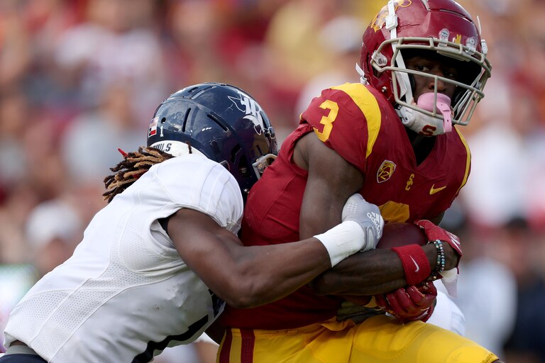 LOS ANGELES, CALIFORNIA - SEPTEMBER 03: Jordan Addison #3 of the USC Trojans is tackled by Sean Fresch #1 of the Rice Owls after his catch during a 66-14 Trojans win over the Rice Owls at United Airlines Field at the Los Angeles Memorial Coliseum on September 03, 2022 in Los Angeles, California.