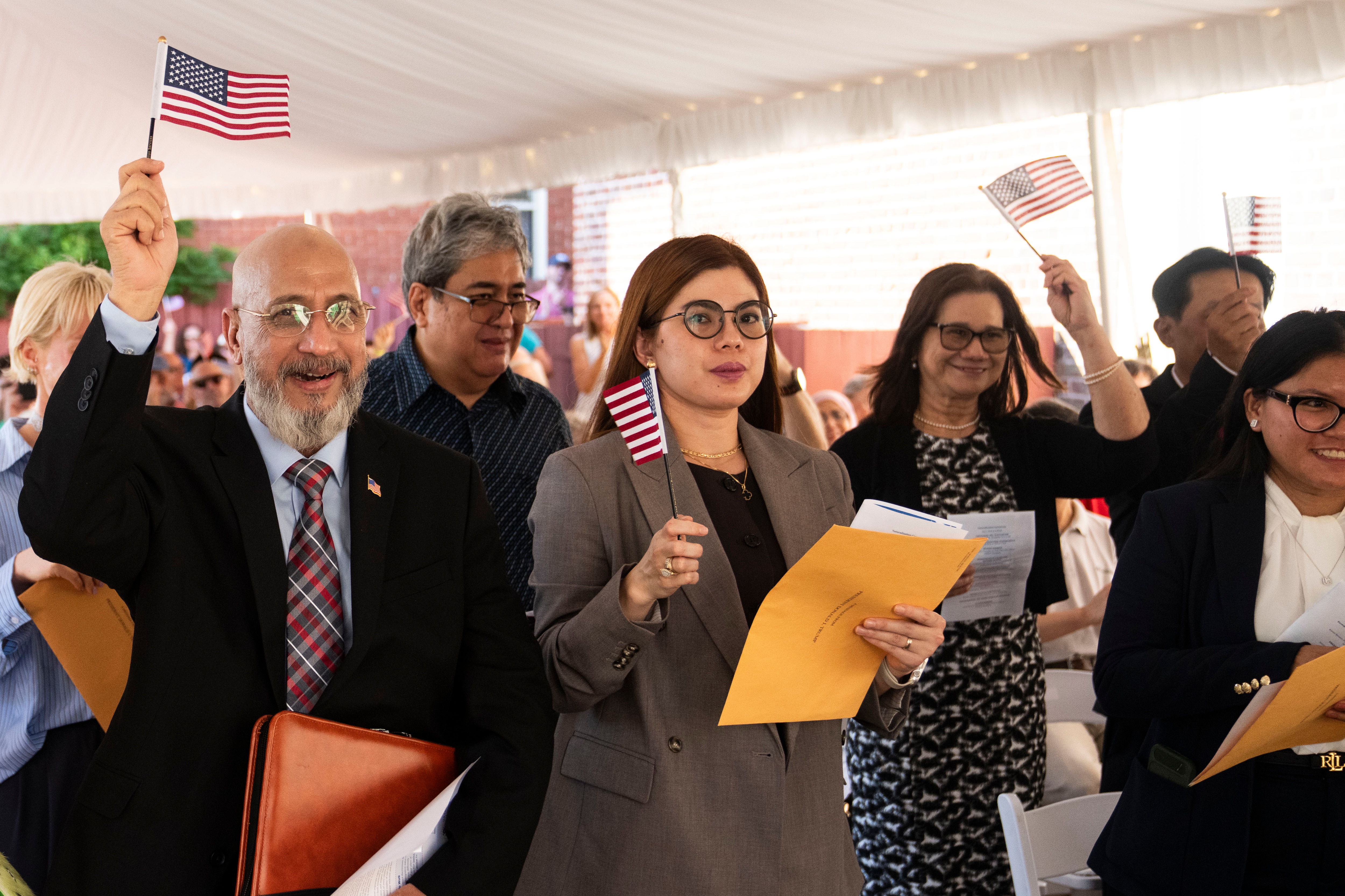 MD Abdullahel Karim of is the first to raise his flag in the air after taking the oath of allegiance to become a Unites States Citizen during a naturalization ceremony at the historic Paca House in Annapolis on Friday.