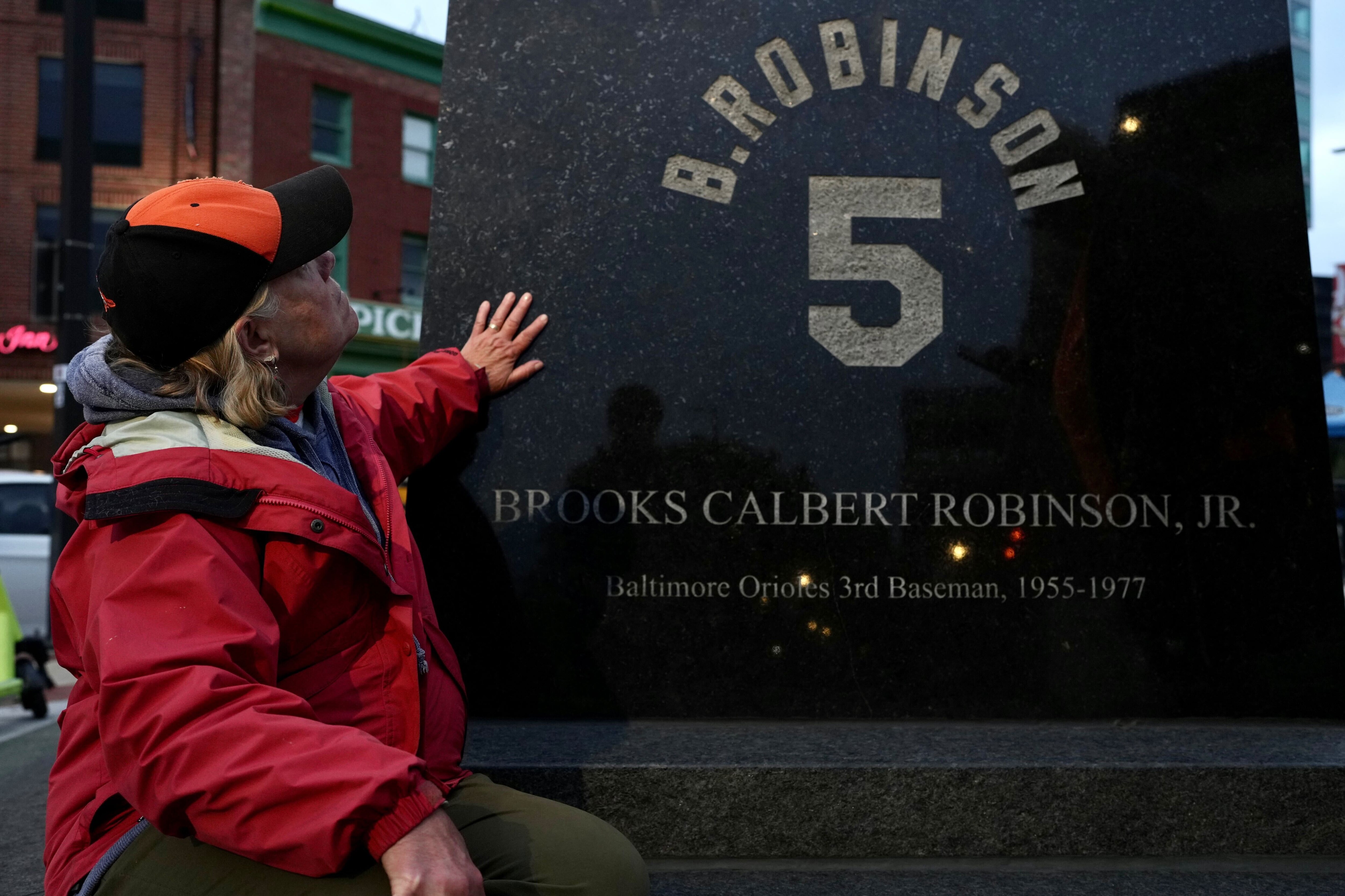 Val Kuciauskas places her hand on the statue of Brooks Robinson outside Camden Yards after hearing of his passing Tuesday night.