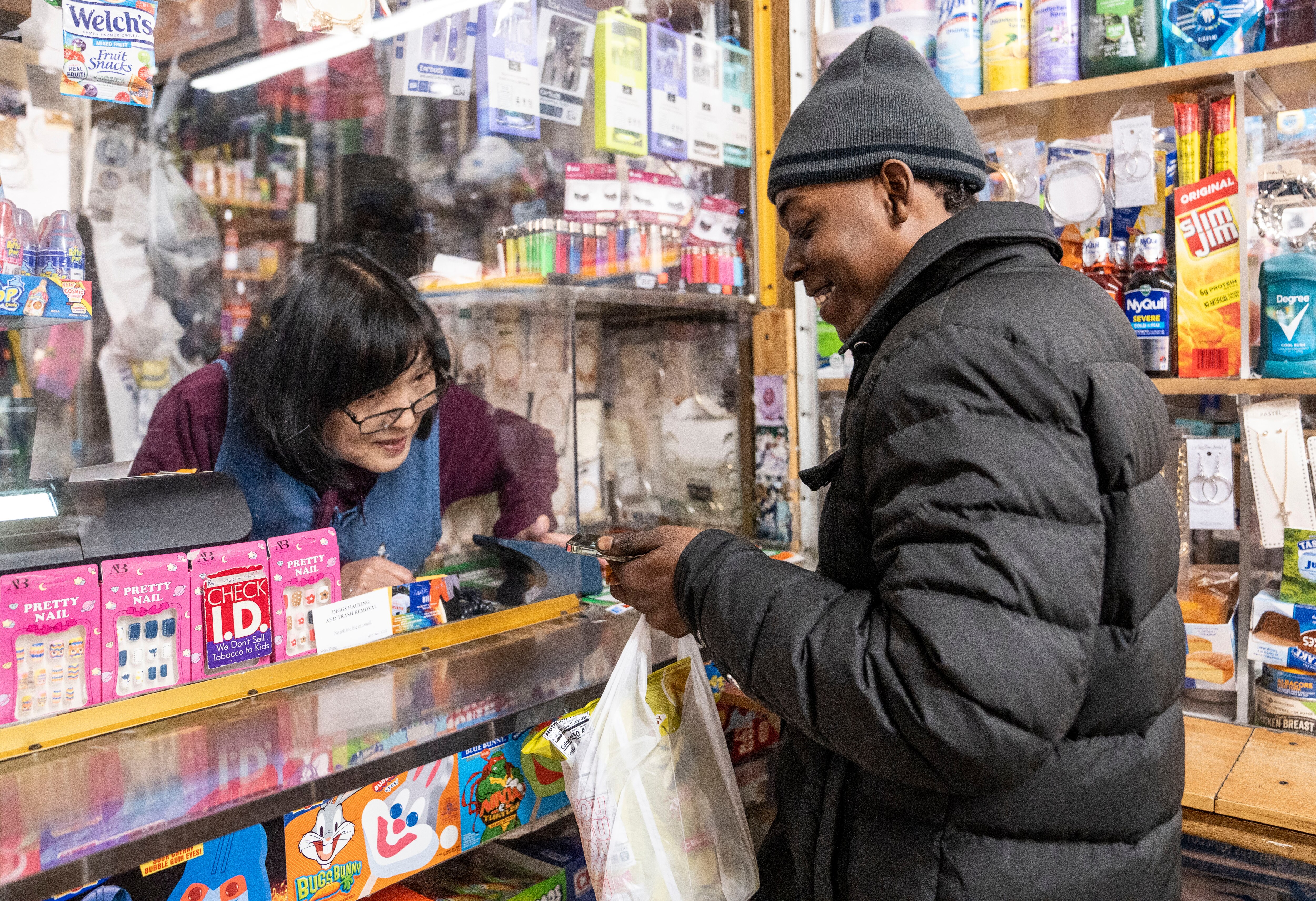Tae Soon Lee talks to Der'eek Fields’ girlfriend who is on speaker phone as he checks out, at Lee's Mini Market, in Baltimore, Thursday, December 1, 2022.