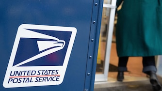 A United States Postal Service mail collection box is seen as a person walks in to the USPS building on Tuesday, Jan. 6, 2026, in Portland, Ore. (AP Photo/Jenny Kane)