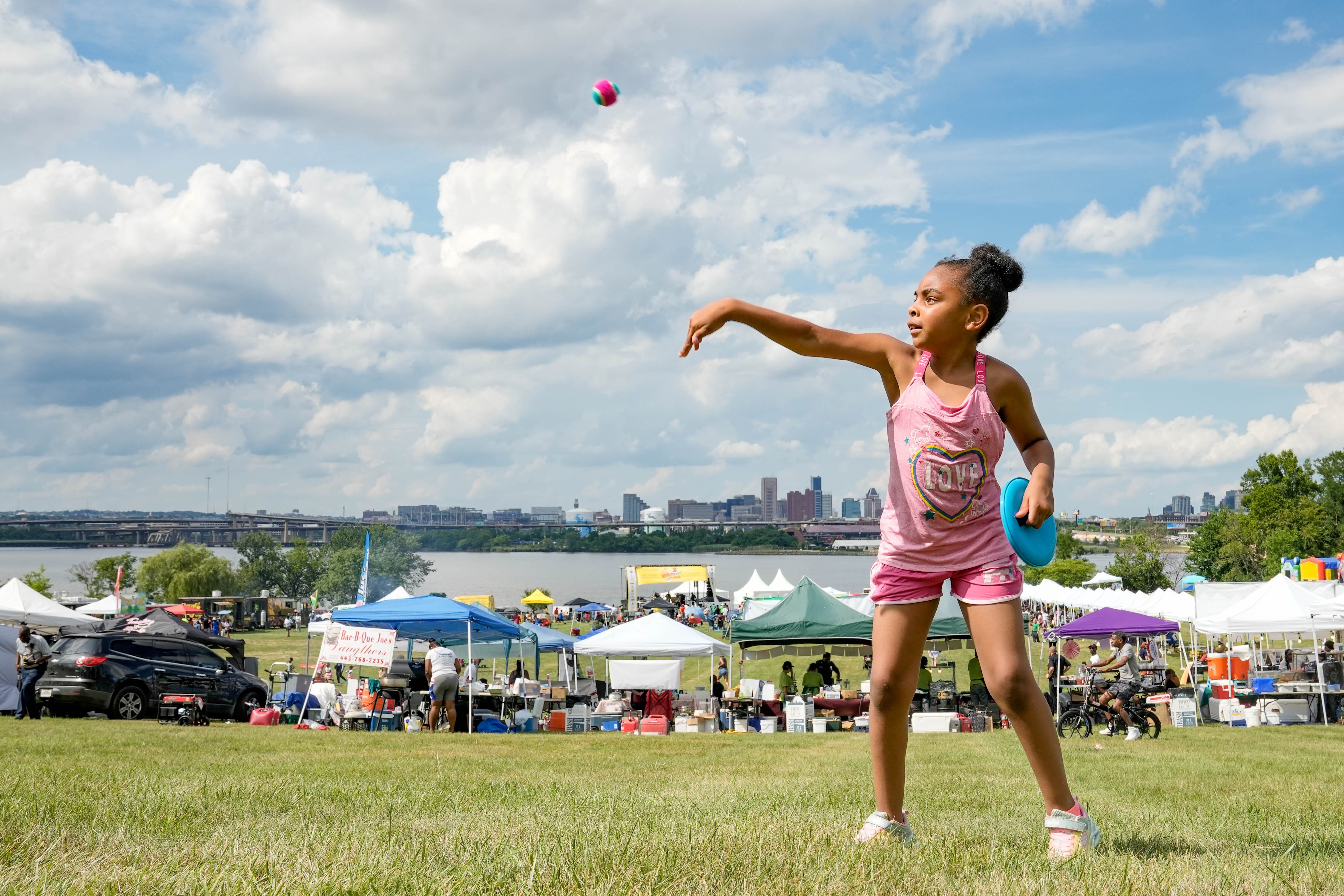 Saniyah Webb throws a ball to her grandfather at the Cherry Hill Arts & Music Waterfront Festival on July 4, 2023.