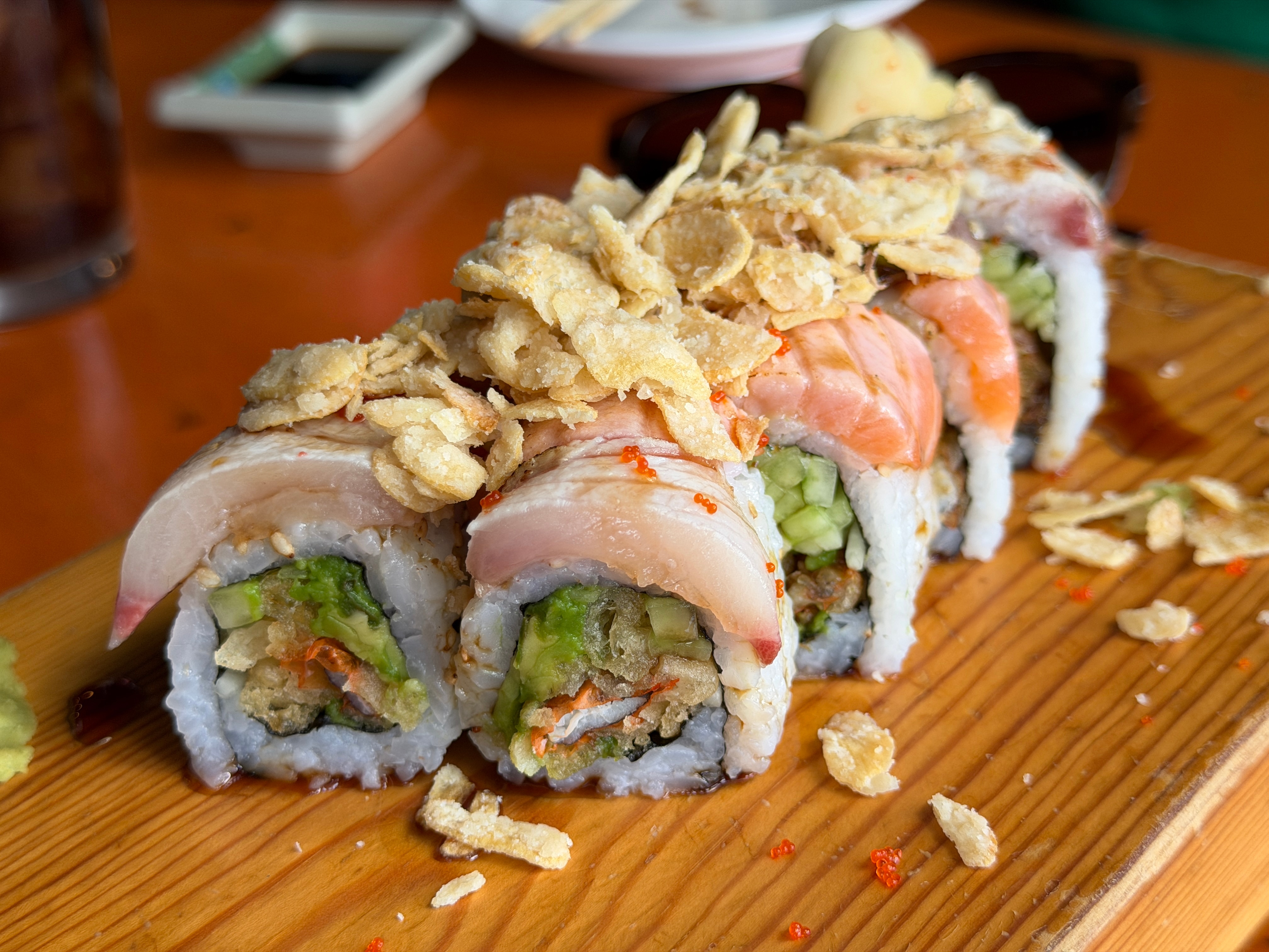 Nanami Cafe's Garlick roll has soft-shell crab tempura, avocado and cucumber inside, is topped with seared salmon and yellowtail, and finished with masago, garlic chips, scallion, ponzu sauce and black garlic sauce.