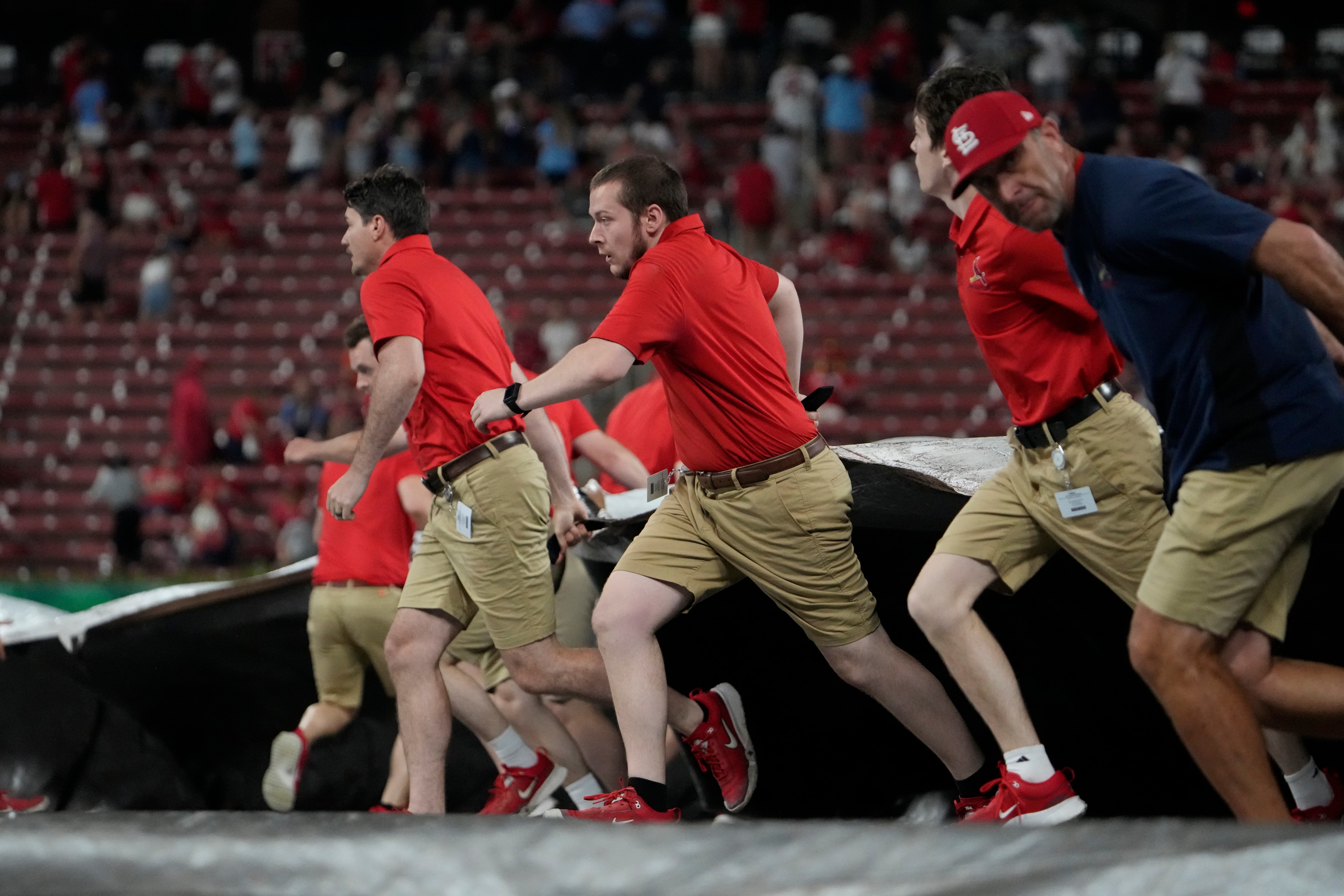 Members of the Busch Stadium grounds crew rush to unfurl the tarp as a storm approaches at the start of a rain delay during the sixth inning. (AP Photo/Jeff Roberson)