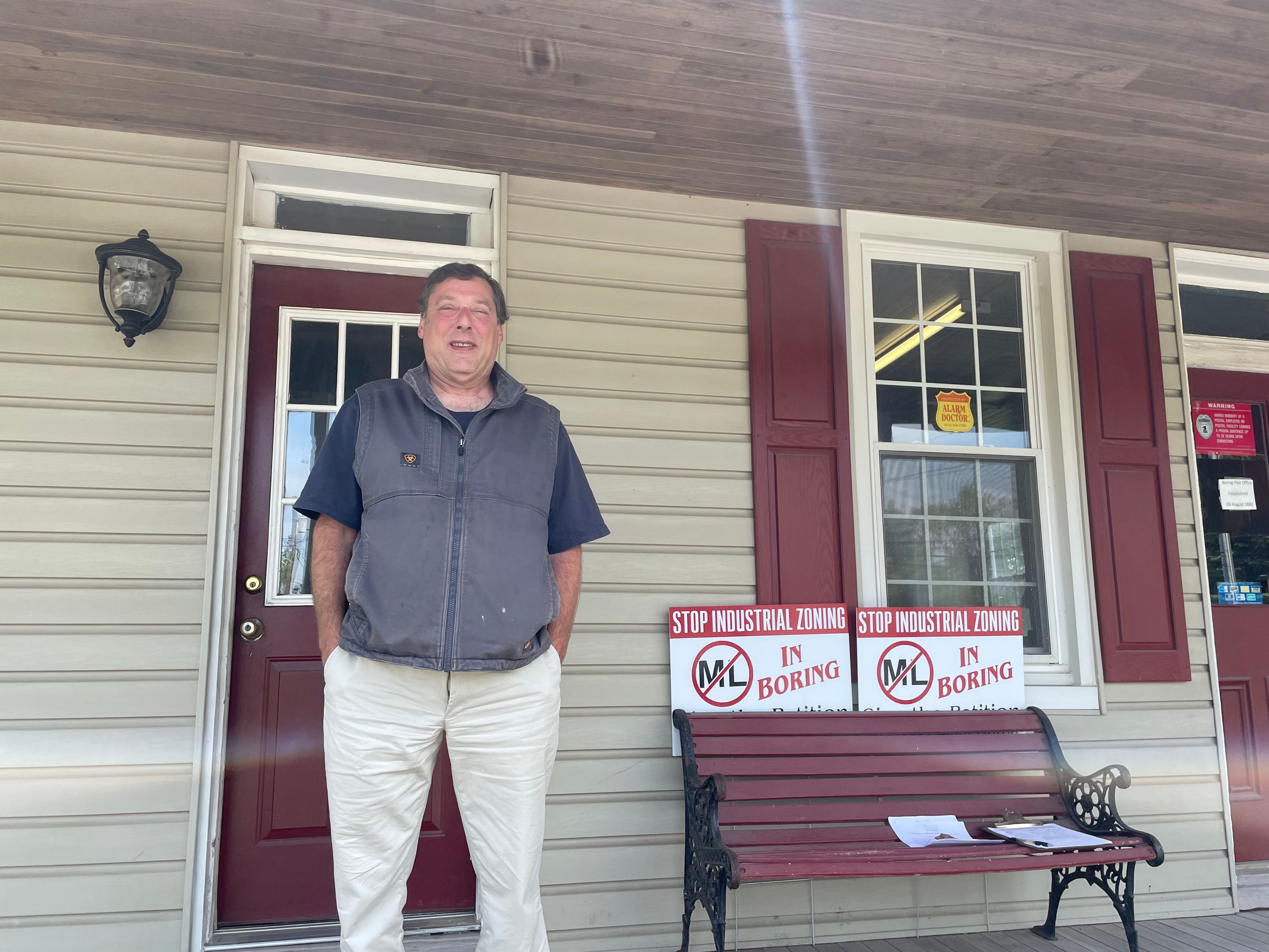 James Blum stands in front of his office and the Boring post office, just across the railroad tracks from the Boring fire hall. He and his family are trying to preserve the community's rural character. A zoning vote on Aug. 27 could change the fire hall into an industrial site, which he has been fighting for years.