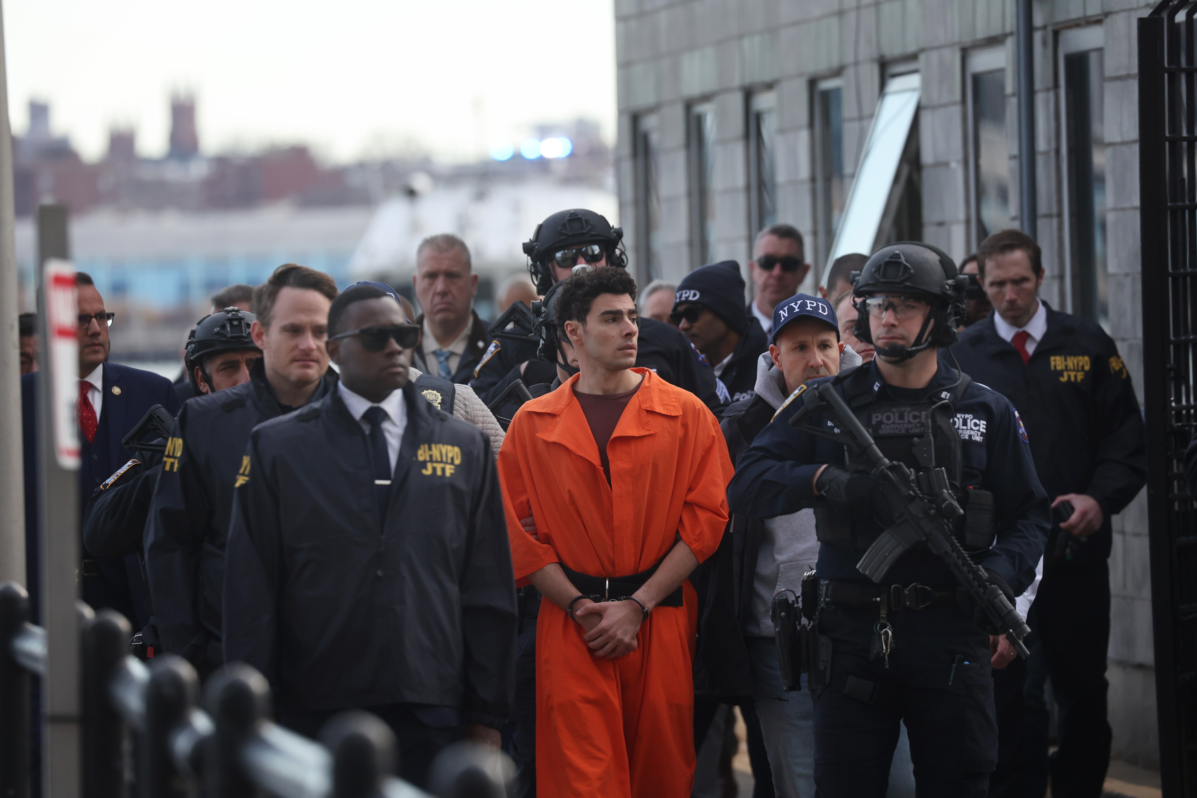 Luigi Mangione, suspect in the killing of UnitedHealthcare CEO Brian Thompson in New York City, arrives at a heliport with members of the NYPD on Thursday in New York City.