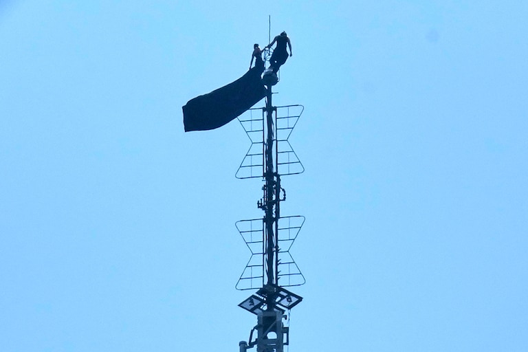Two people stand on the tip of the antenna of the Empire State Building while holding a banner on Wednesday, July 1, 2026.