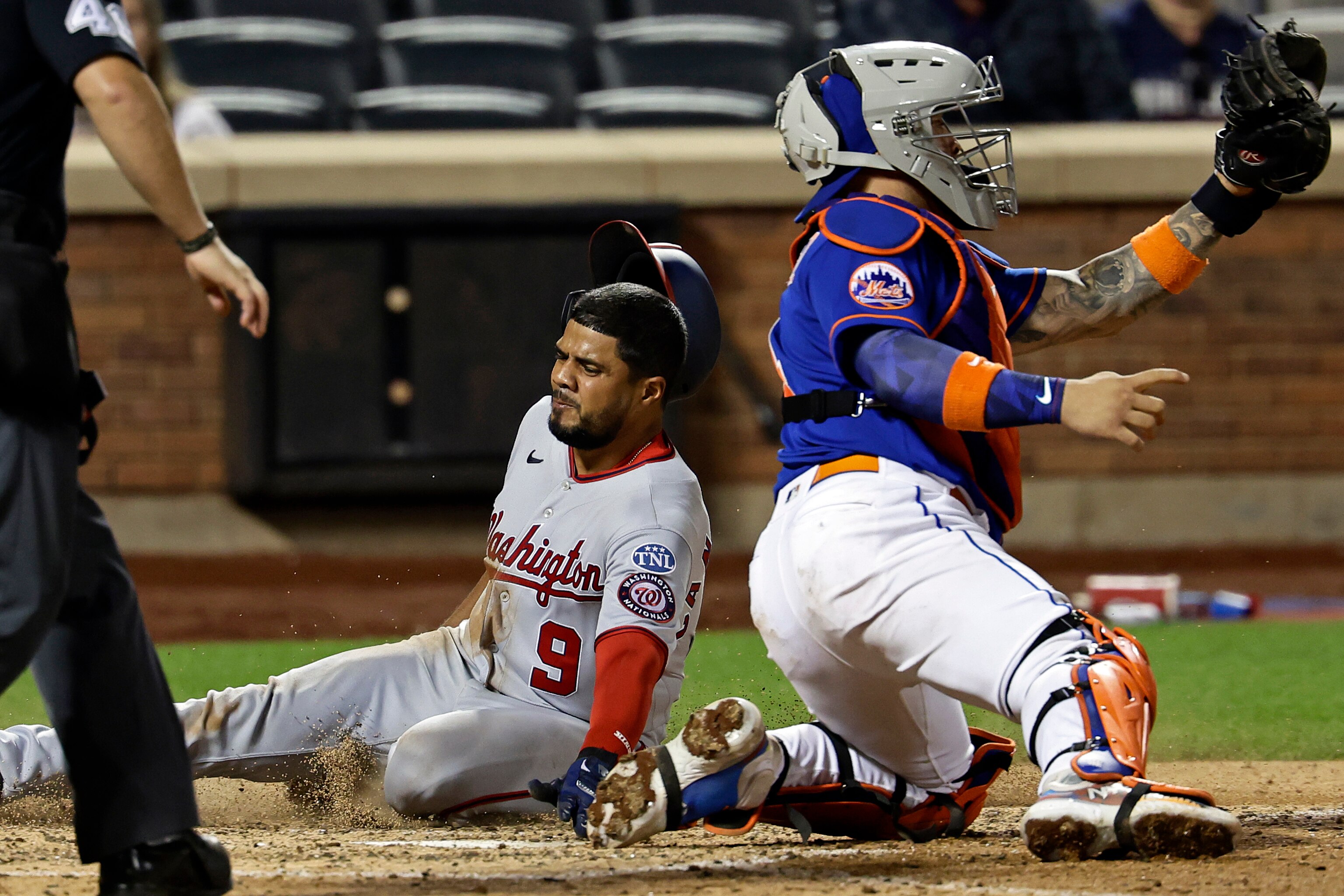 The Nationals' Jeimer Candelario slides past Mets catcher Francisco Alvarez to score a run in the ninth inning.