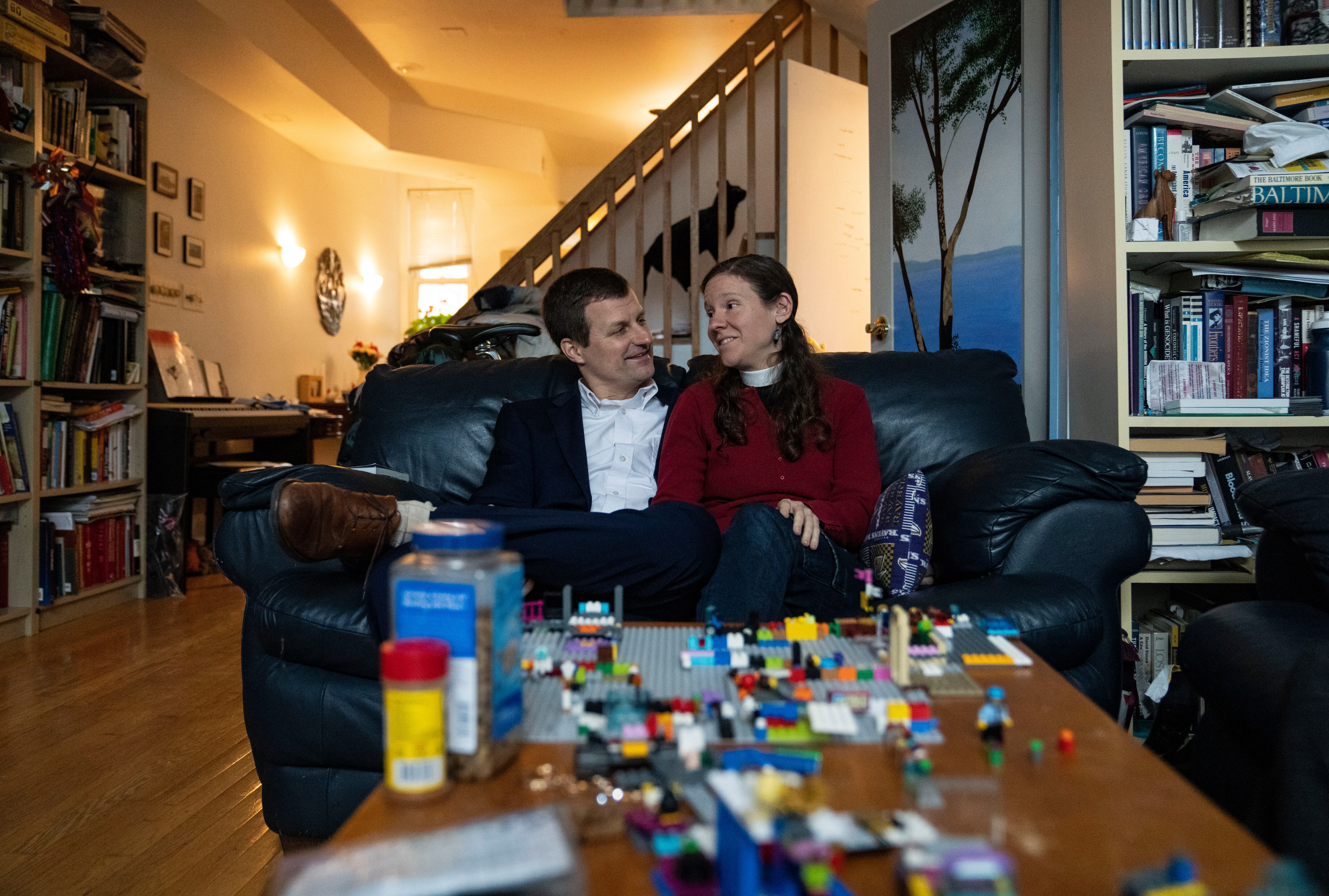 Mark Parker and Christine Parker sit for a portrait on their couch in their home in Baltimore, Thursday, February 13, 2025.