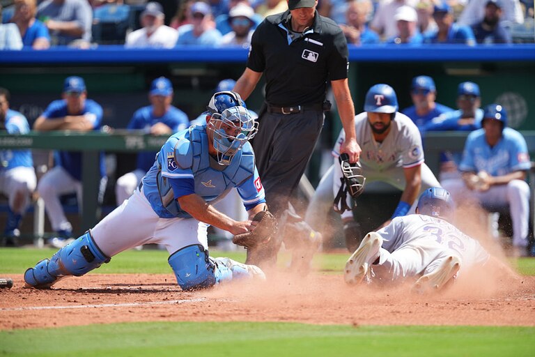 Evan Carter #32 of the Texas Rangers scores against Luke Maile #17 of the Kansas City Royals in the fifth inning on Aug. 21.