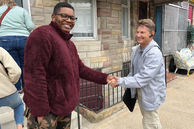 A local homebury and a representative from Habitat for Humanity Chesapeake shake hands in front of a newly purchased rowhome.