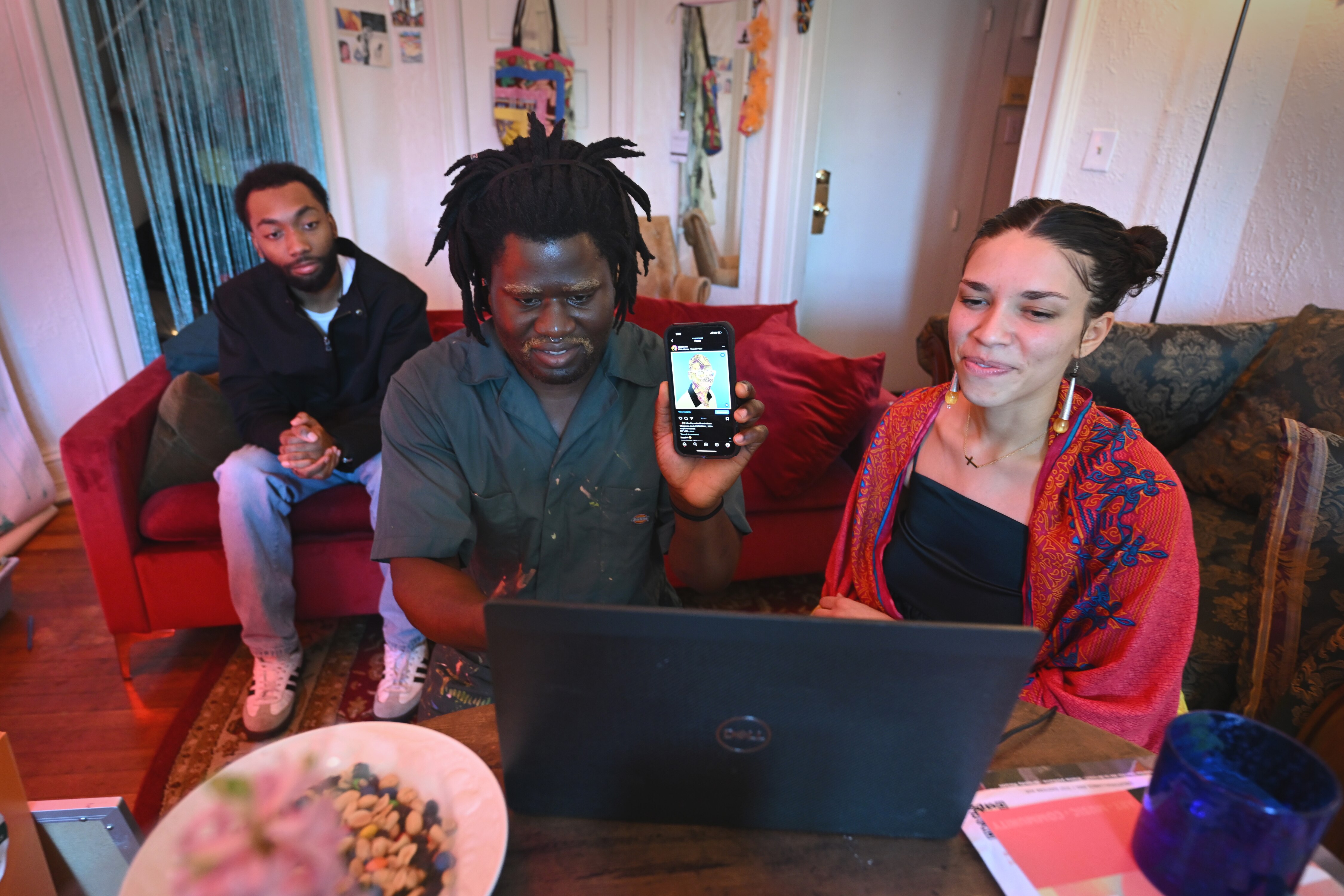 Ariel Barbosa, right, in her Baltimore apartment with Villager, center, and Roy Byrd while they meet remotely with artists in Brazil on Sunday, Feb. 4, 2024. The artists are members of A Gente, which is an exchange between Black artists in Baltimore and Brazil that engage in deep dialogue and immerse into local culture and their art.