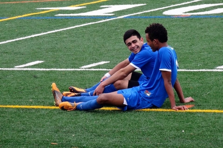 Warshan Hussin laughs with a teammate during his time playing with Soccer Without Borders.