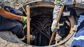 Employees of the city’s conduit division replace a cracked manhole on Cathedral Street in Mount Vernon