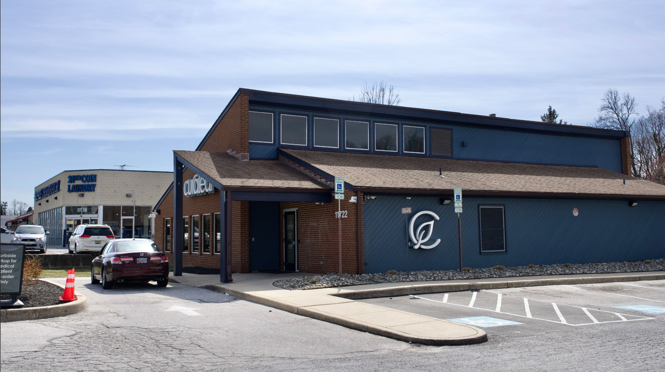 The outside of Curaleaf features the company's logo, which is a leaf inside the letter C, on a blue wall.