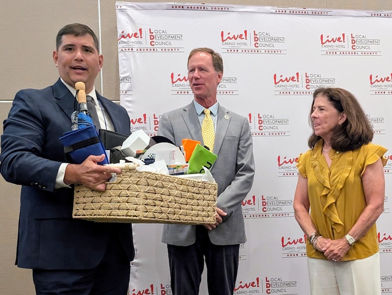 Karen McJunkin, outgoing chair of the Anne Arundel County Local Development Committee, receives gifts from, left, Christopher Maruyama, project manager for Anne Arundel Community Development Services, and County Executive Steuart Pittman.