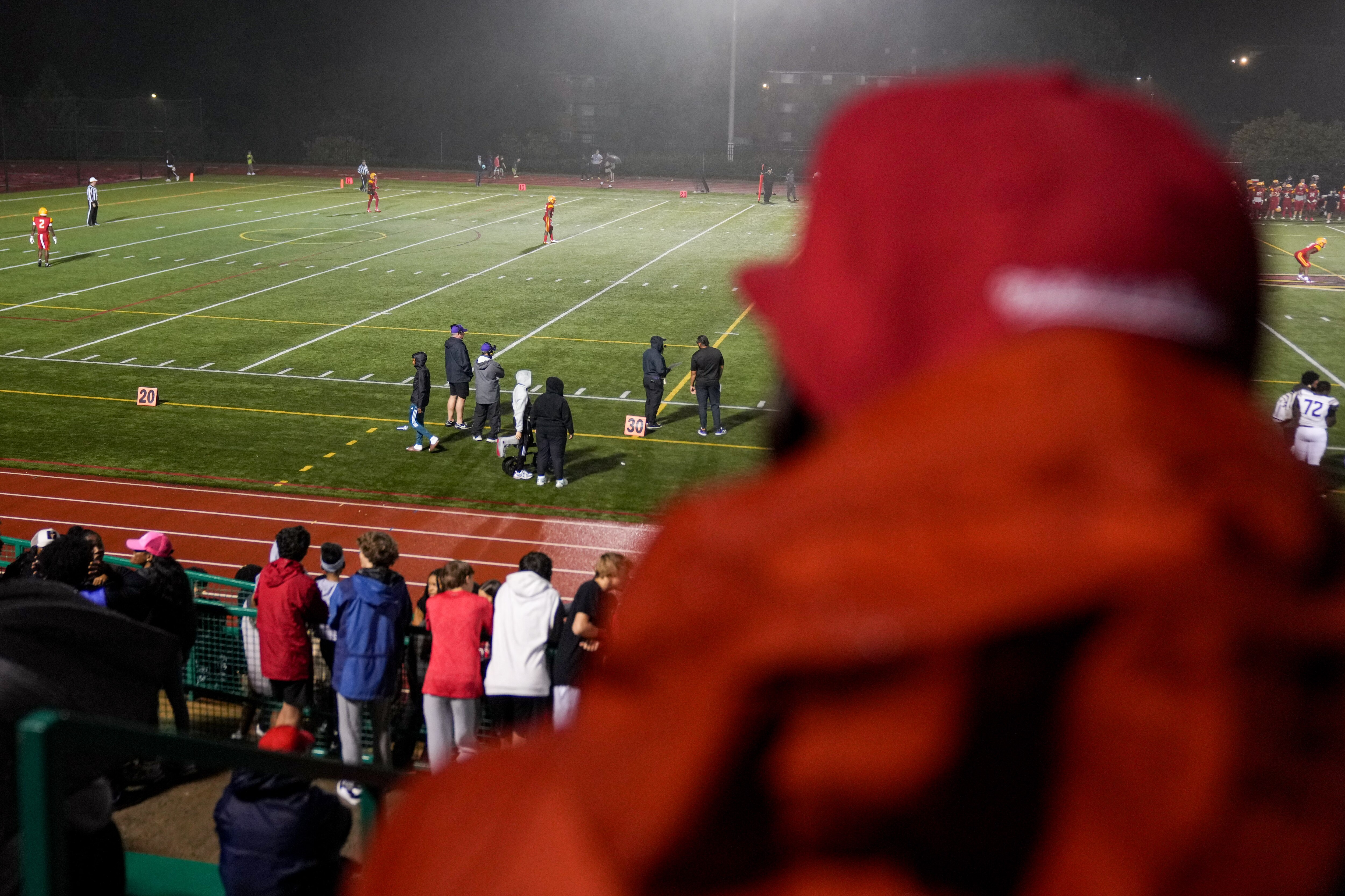 Baltimore Ravens assistant head coach Chris Hewitt watches as his son, Chris Hewitt Jr. (far left on field), plays in a football game between Calvert Hall and Mount Saint Joseph in September.