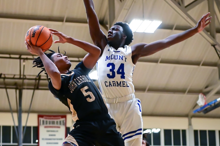 John Carroll's Caden Chinnia-Falline (5) tries to shoot against Mount Carmel's Allen Mordi during Friday night's Baltimore Catholic League Tournament quarterfinal match. The No. 6 Cougars advanced to the semifinals with a 79-63 victory over the Patriots at Goucher College.