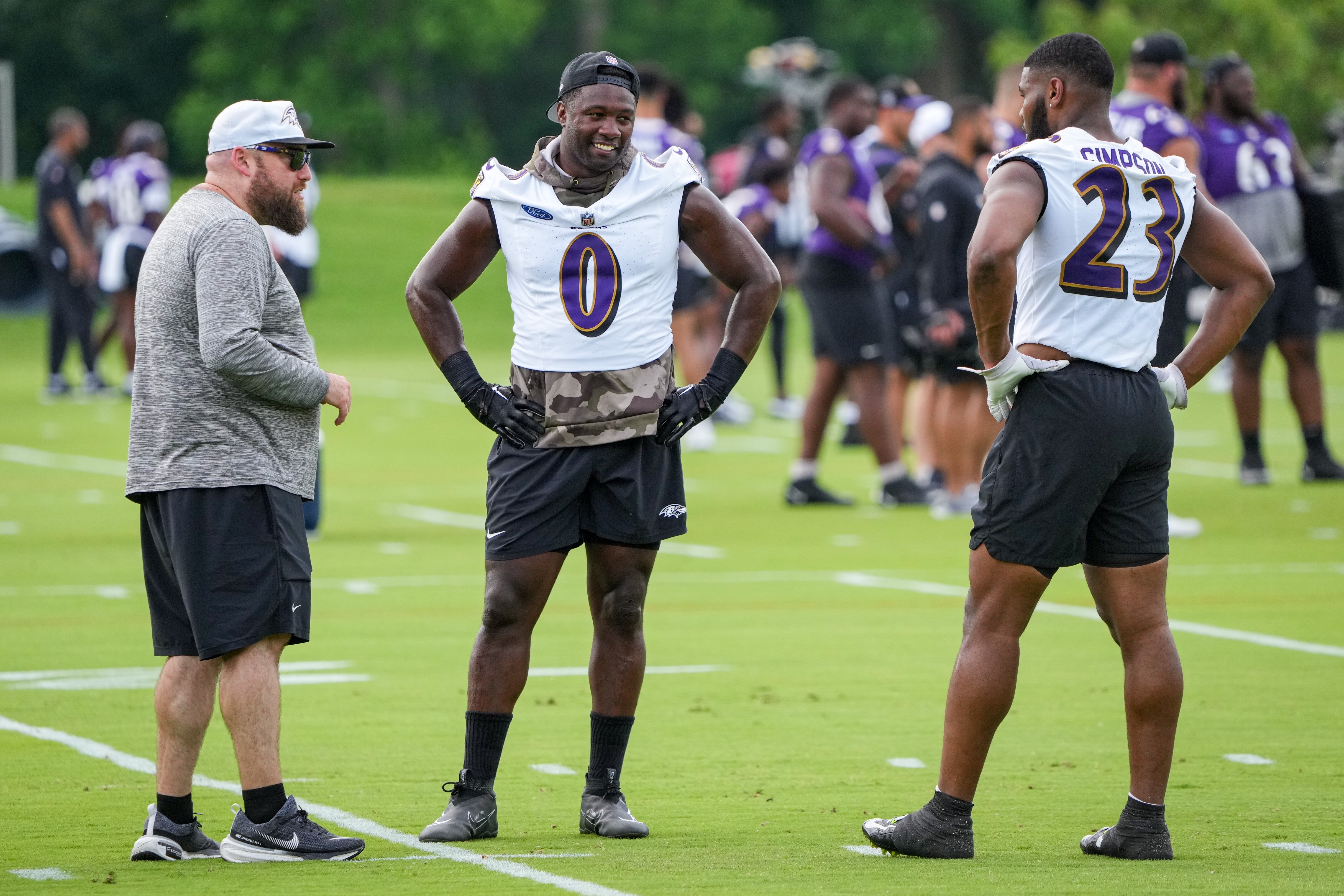 Inside Linebackers Coach Mark DeLeone (left) speaks with linebackers Roquan Smith (0) and Trenton Simpson (23) between drills during the Baltimore Ravens’ organized team activities at the Under Armour Performance Center in Owings Mills on June 4, 2024.