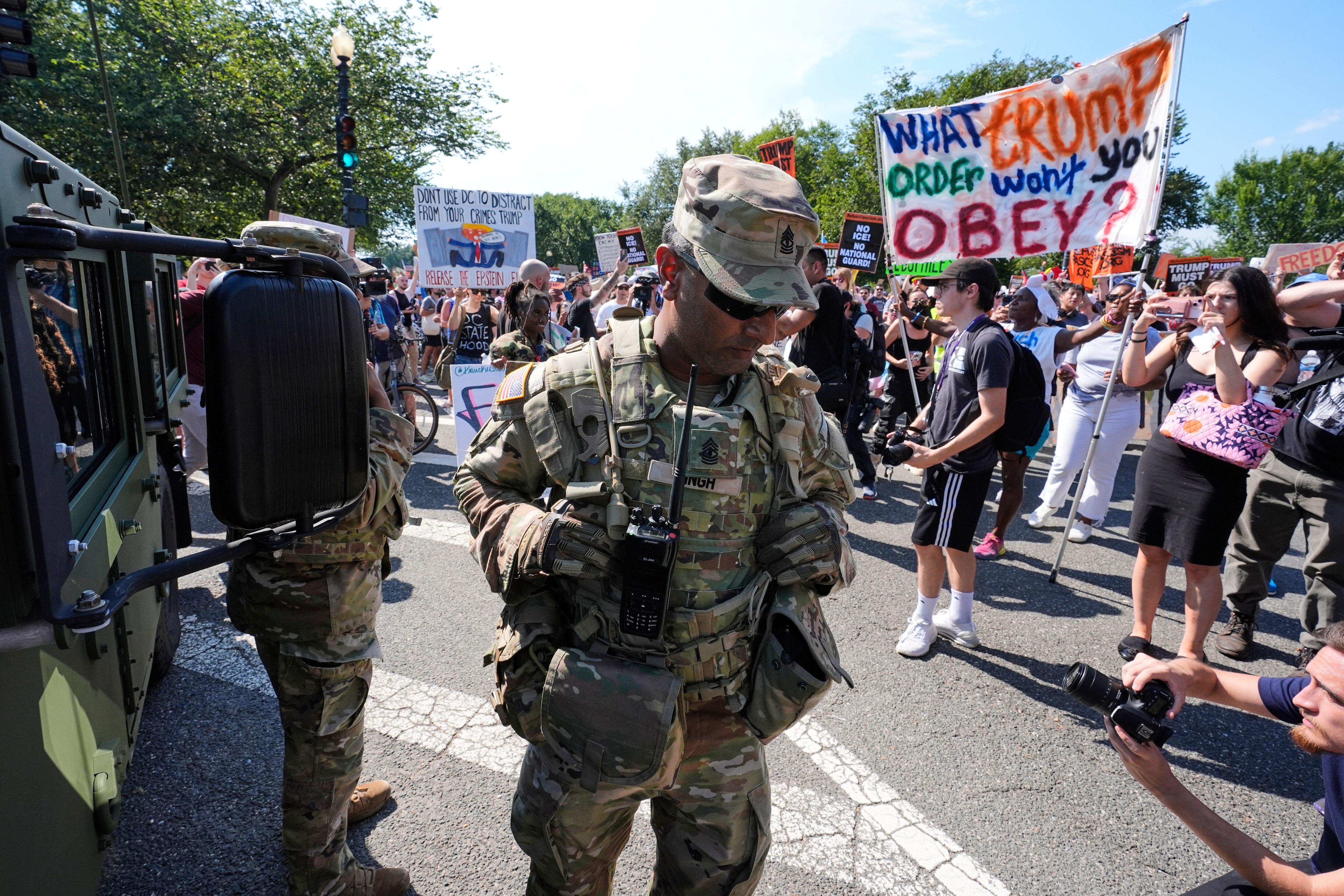 A first sergeant with the District of Columbia National Guard watches as activists protest President Donald Trump's federal takeover of policing of the District of Columbia, Saturday, Aug. 16, 2025, in Washington. (AP Photo/Alex Brandon)