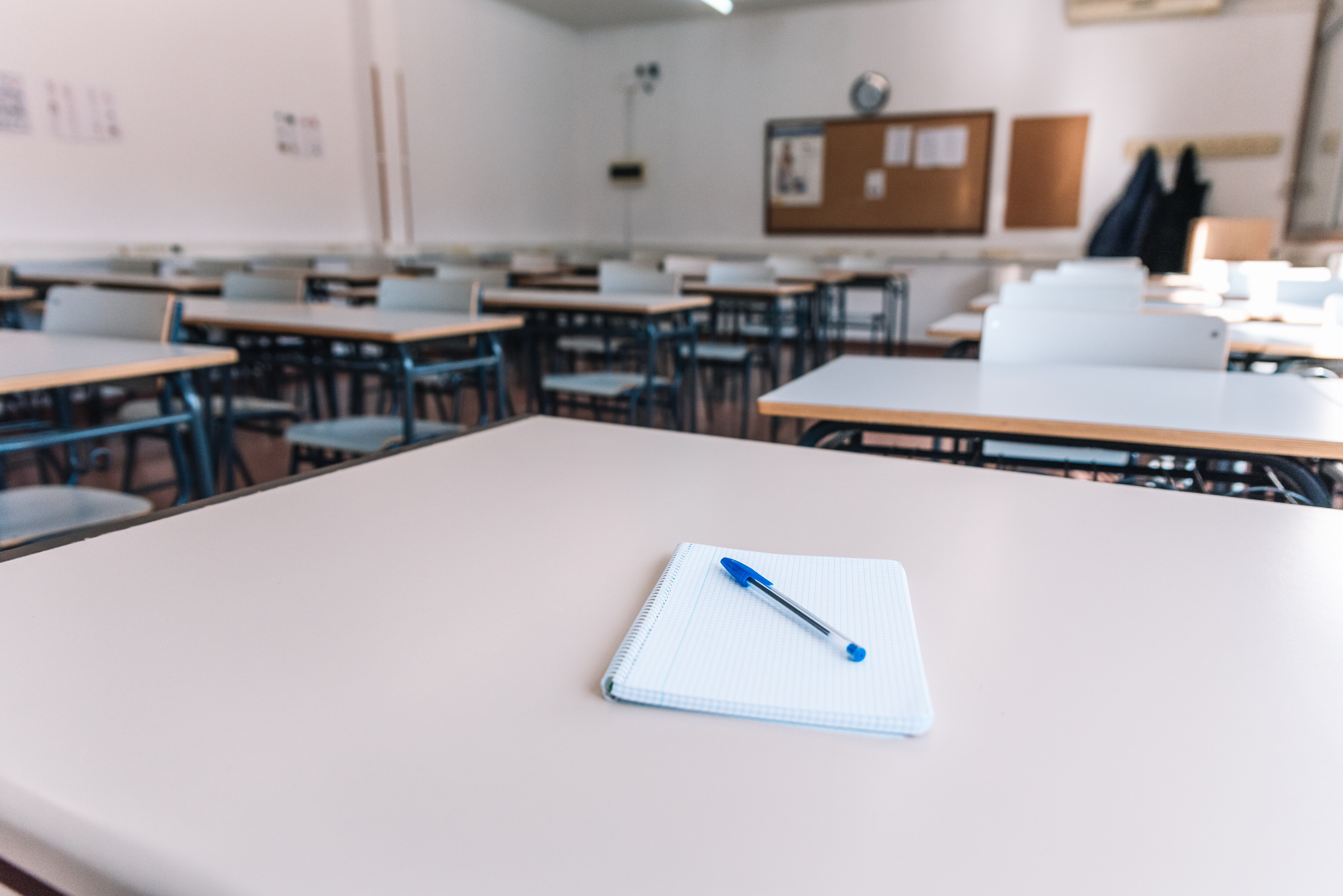 Notebook with a pen on a table in a classroom at a school.