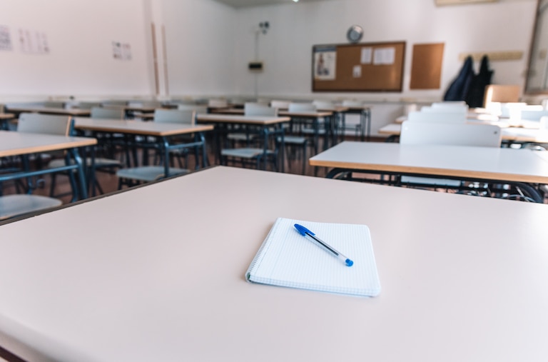 Notebook with a pen on a table in a classroom at a school.