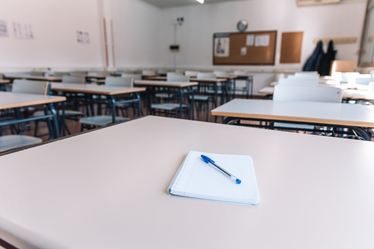 Notebook with a pen on a table in a classroom at a school.