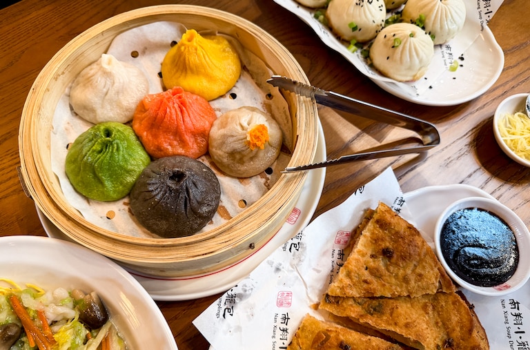A spread of dishes at Nan Xiang Soup Dumplings includes a side of shredded ginger for diners to add soy sauce, black vinegar and chili oil.