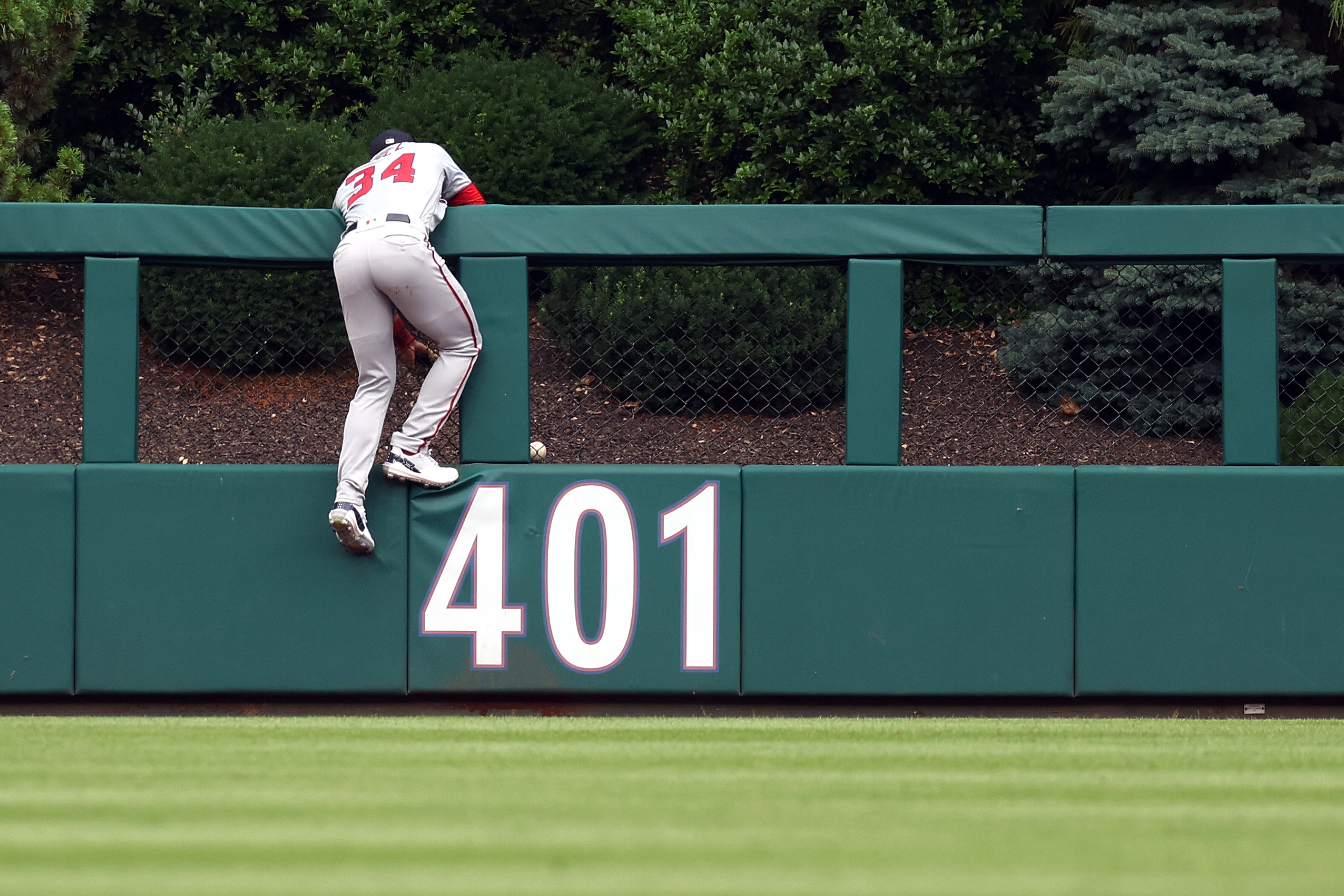 Nationals outfielder Derek Hill climbs the fence in vain in pursuit of a home run by the Phillies Nick Castellanos.