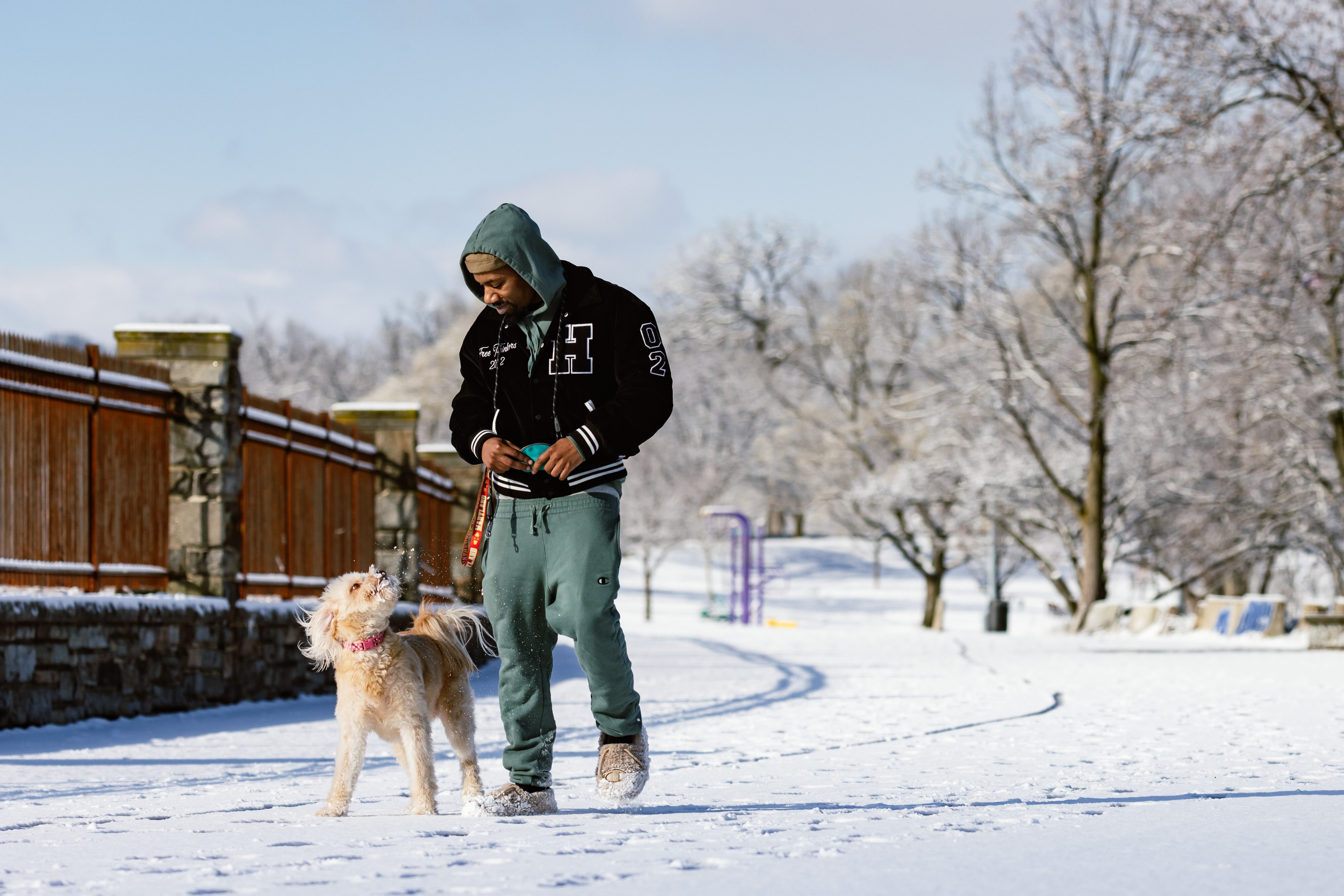 Dantae Fisher and Lacey, a goldendoodle, walk around Druid Lake on Sunday after snow fell overnight.
