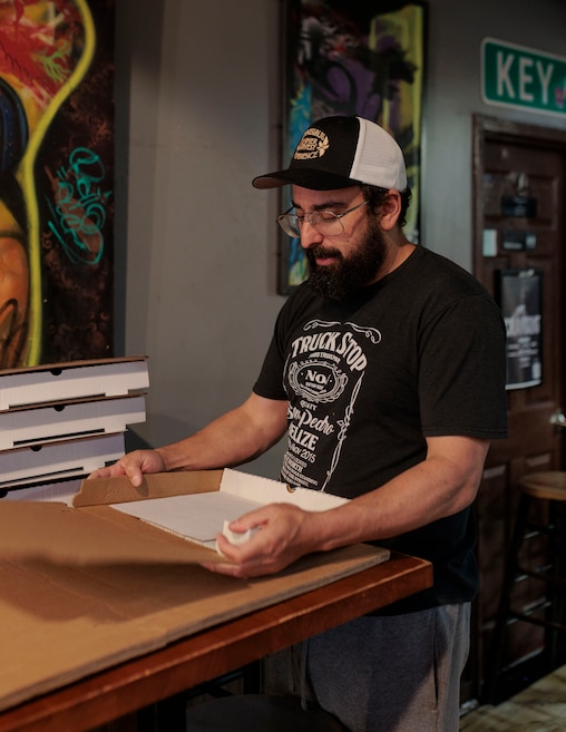 Evan Weinstein, owner of Underground Pizza, folds take out boxes for pizza at the downtown location.