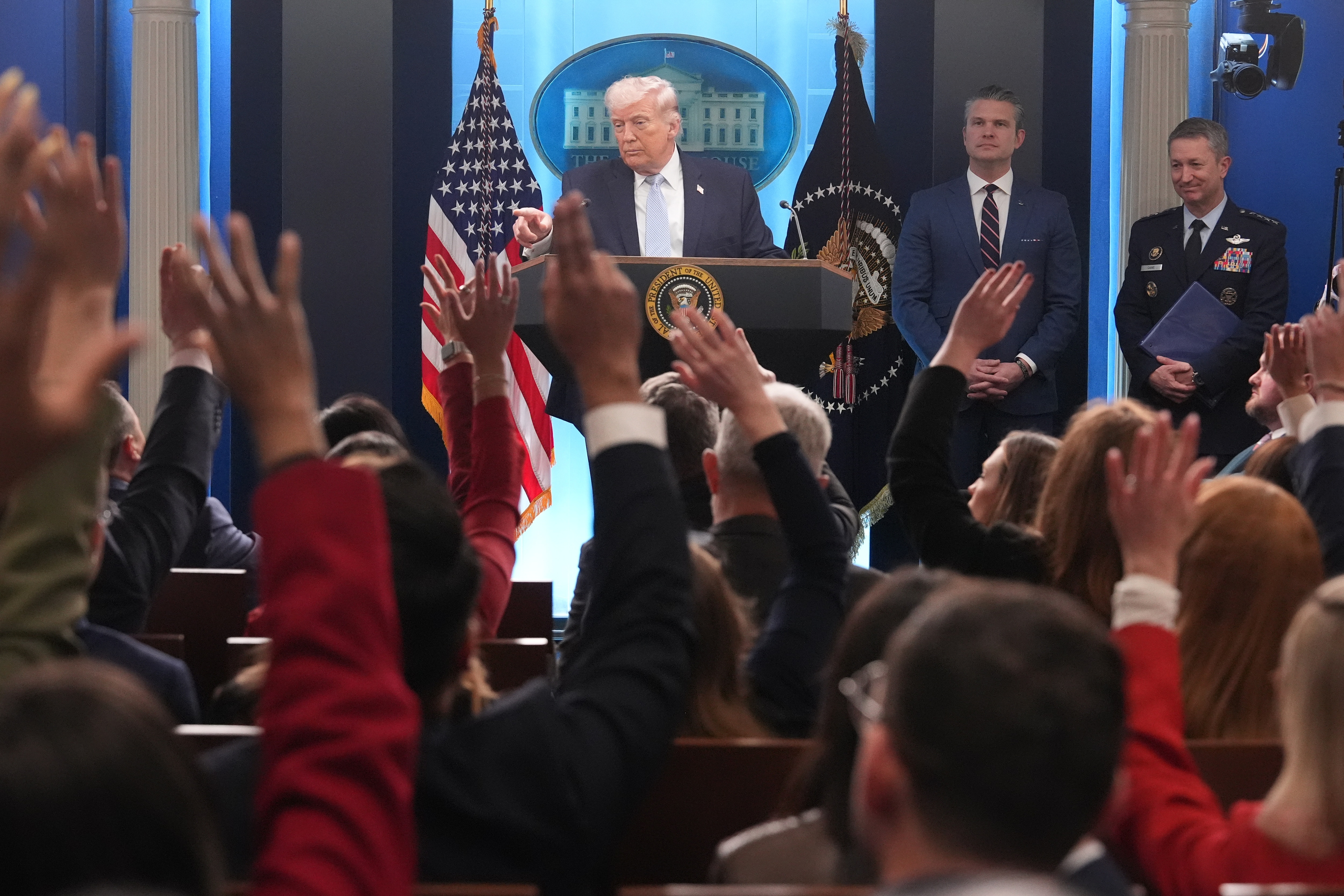 President Donald Trump speaks with reporters during a news conference in the James Brady Press Briefing Room at the White House, Monday, April 6, 2026, in Washington, as Defense Secretary Pete Hegseth and Chairman of the Joint Chiefs of Staff Gen. Dan Caine listen.