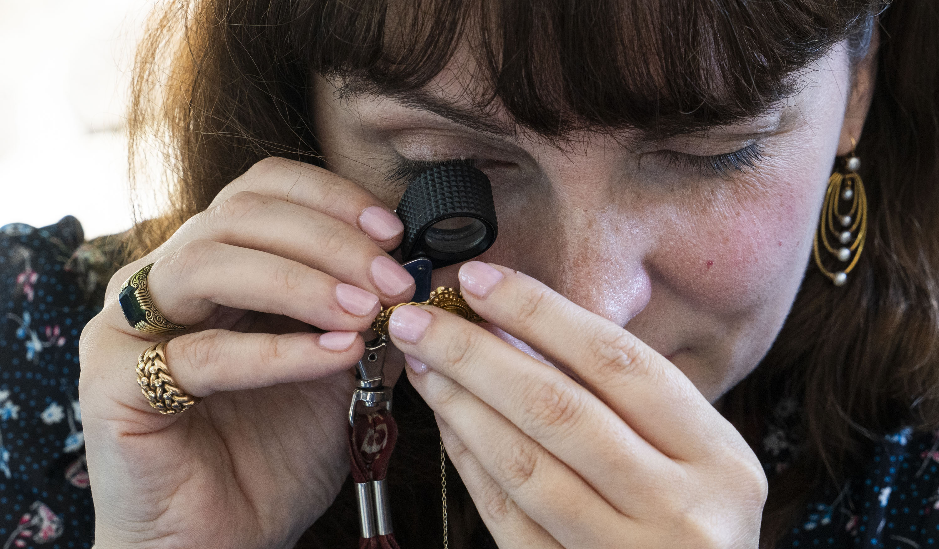 Appraiser Kaitlin Shinnick takes a close-up peek at Banner reporter Kaitlin Newman’s 18th-century diamond and gold brooch at “Antique Roadshows” at the Maryland Zoo.