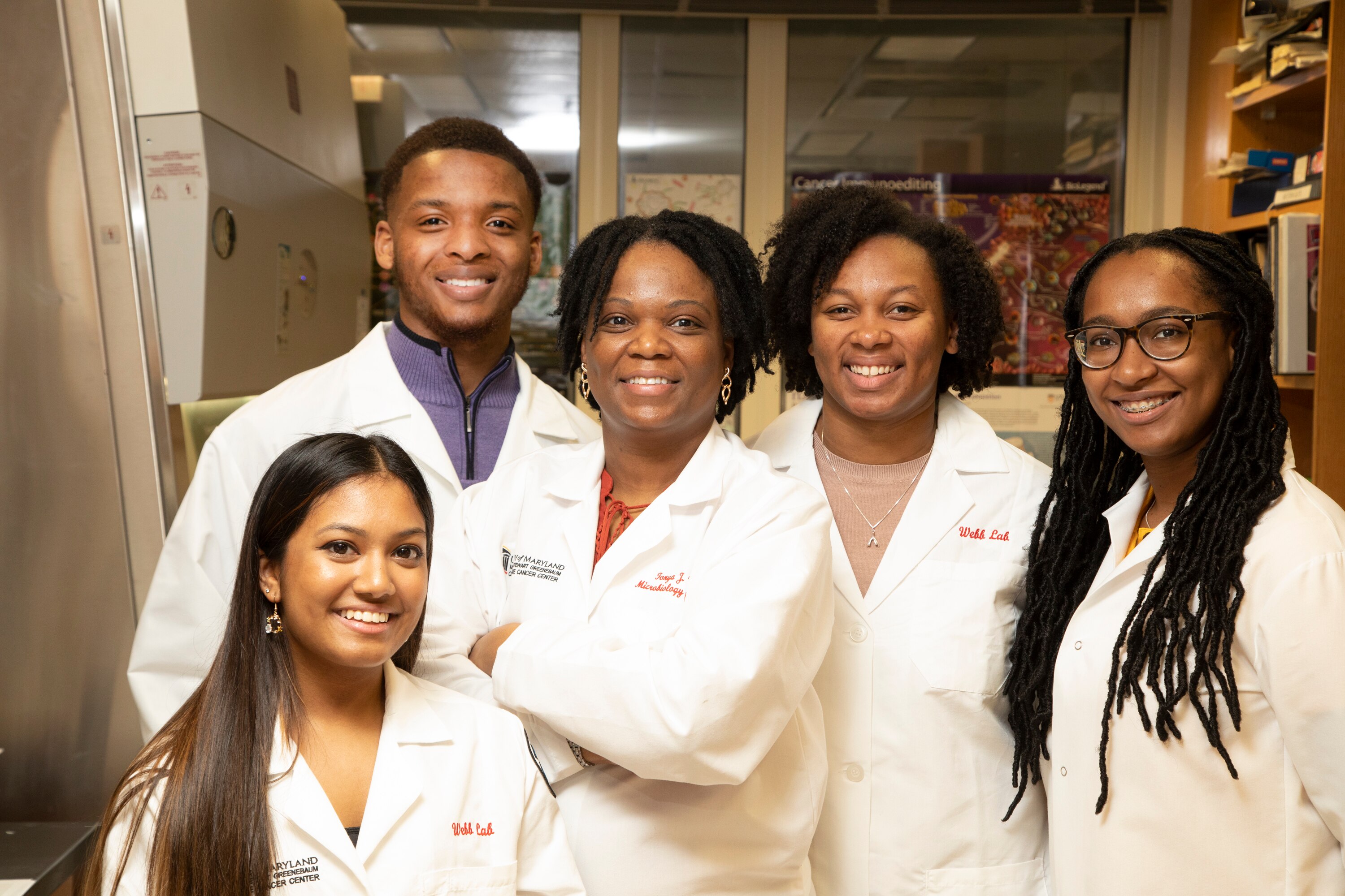 Tonya Webb (center with her arms folded) is an associate professor specializing in microbiology and immunology at the University of Maryland School of Medicine. She also heads up the Diversity In Cancer Research Internship Program.