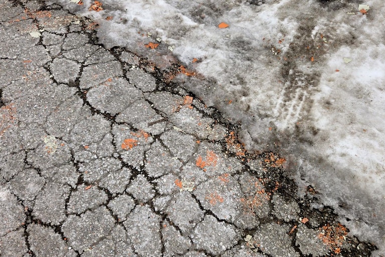 Orange paint chips can be seen on the ground by the edge of the snow, along a property fence on Falls Road.