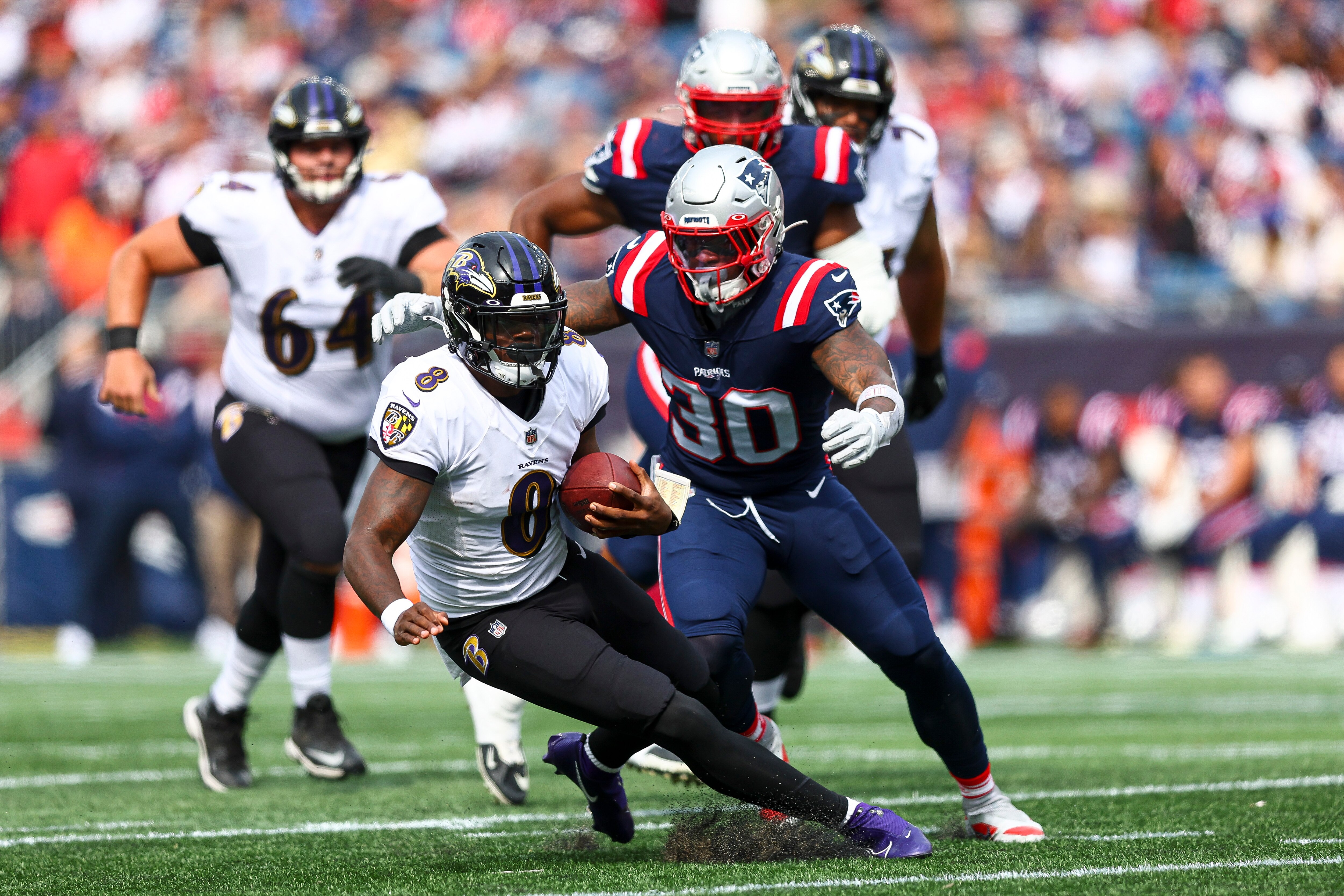 Quarterback Lamar Jackson #8 of the Baltimore Ravens runs past linebacker Mack Wilson Sr. #30 of the New England Patriots during the first half at Gillette Stadium on September 25, 2022 in Foxborough, Massachusetts.