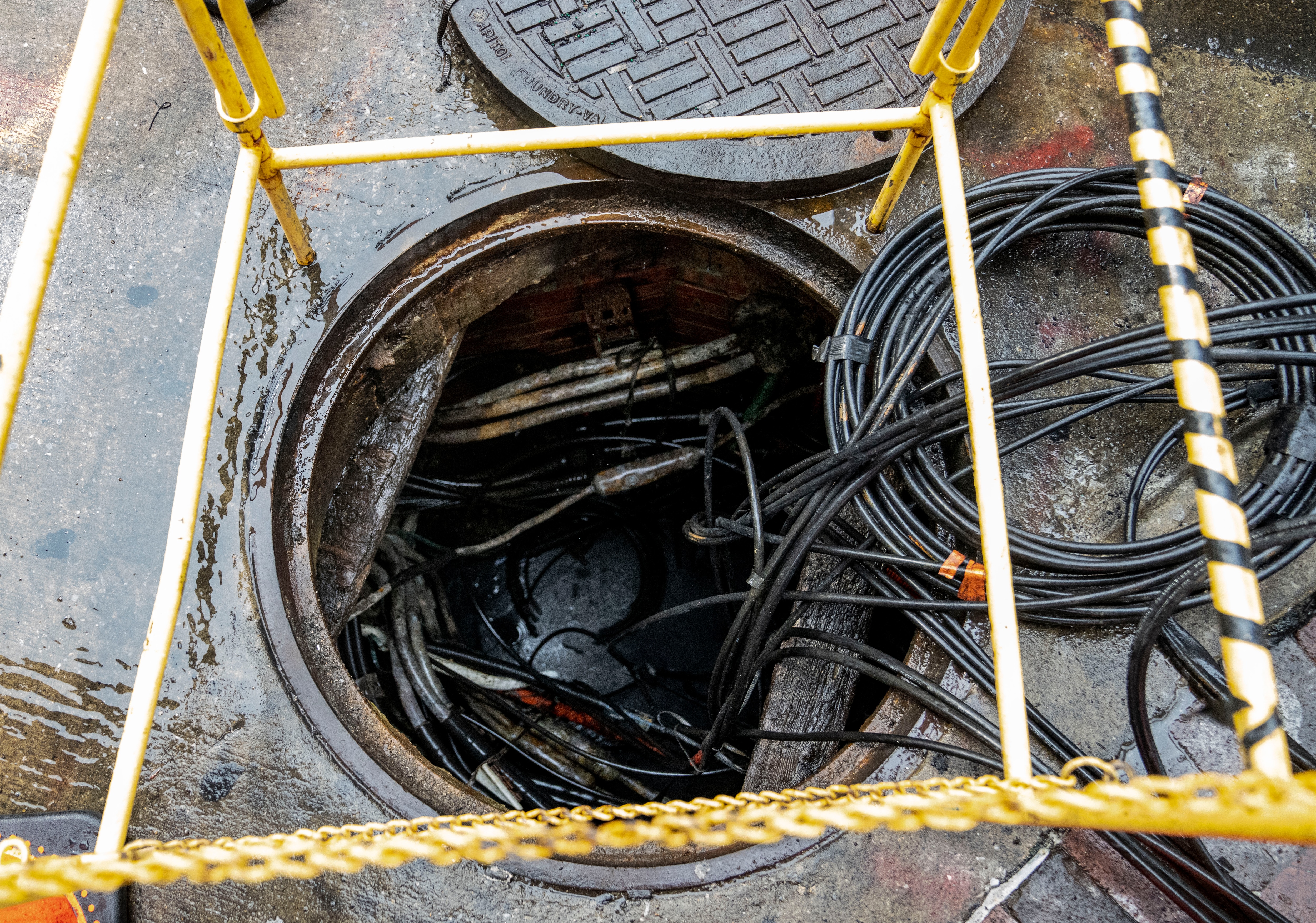 Cords come out of an open manhole cover on North Charles St., in Baltimore, Monday, September 30, 2024.
