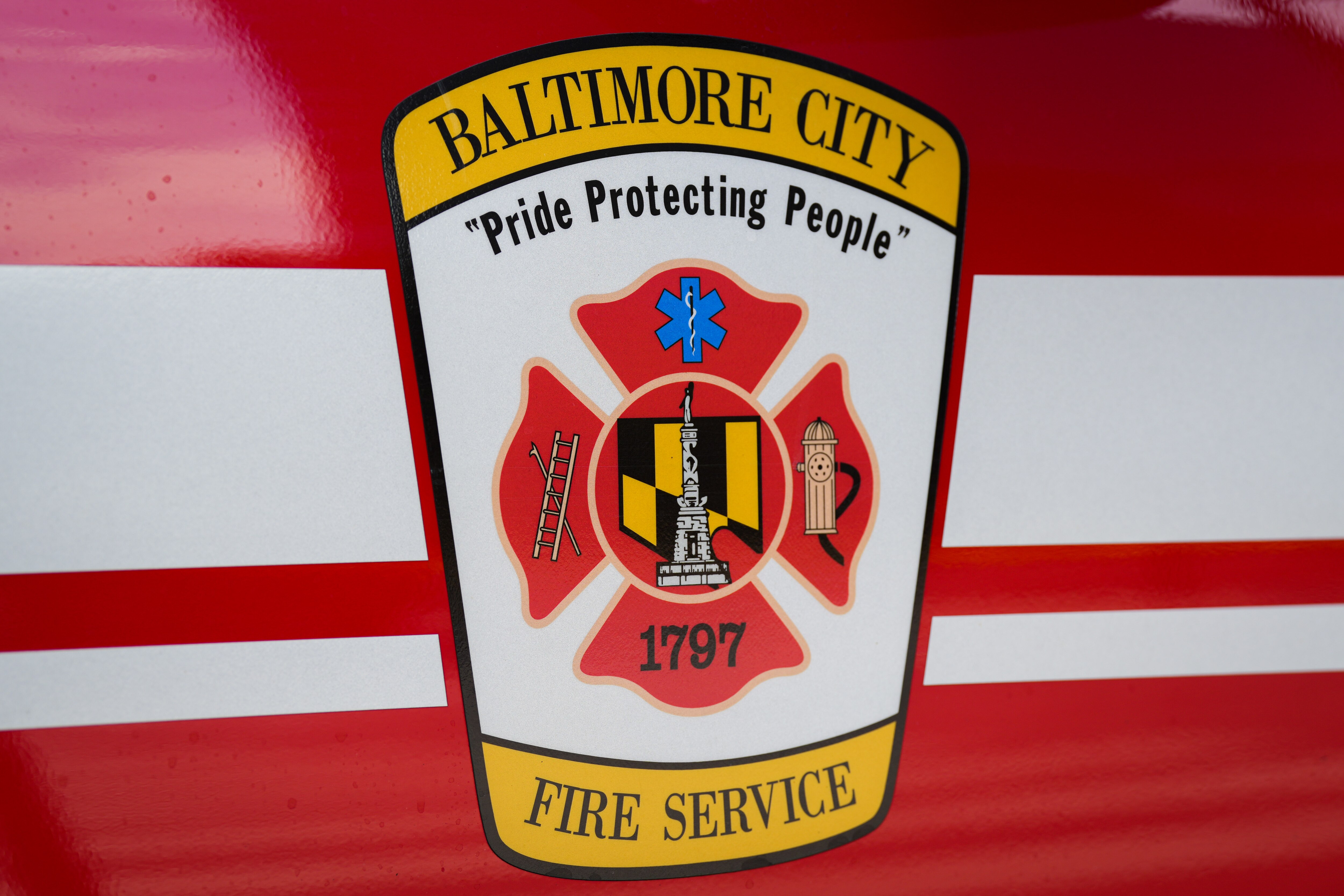 A Baltimore City Fire Service vehicle remains on the scene after a vehicle exploded inside a five-story parking garage in Baltimore’s Fells Point neighborhood on 7/27/22.  Two people are being treated for injuries, fire officials said Wednesday afternoon.