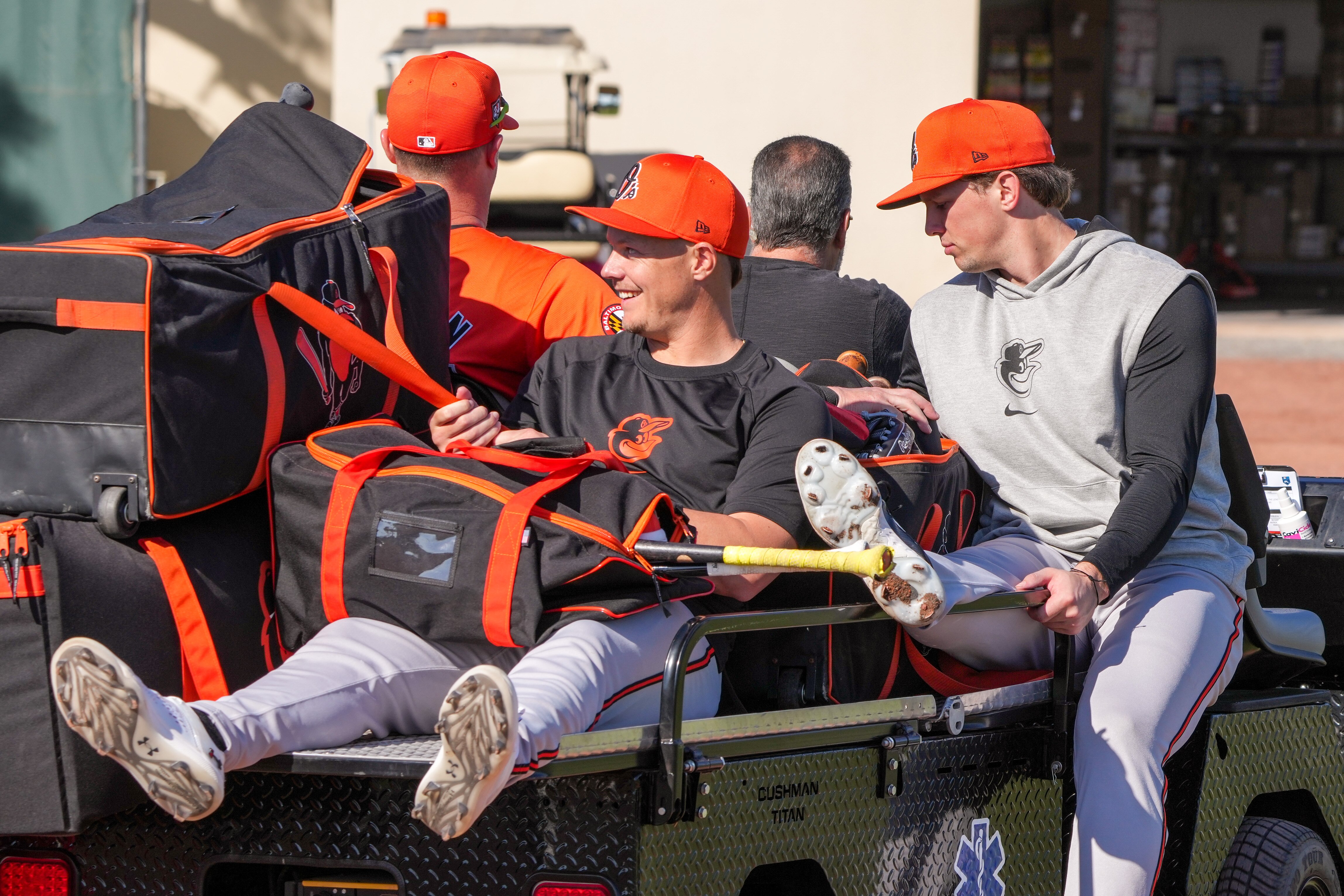 Orioles first baseman Ryan Mountcastle, left, and catcher Adley Rutschman ride a cart to the main field during spring training at Ed Smith Stadium last week.