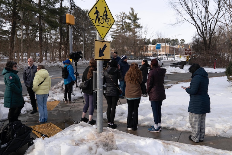 People wait outside Thomas S. Wootton High School for students in Rockville Md., Monday, Feb. 9, 2026, after a person was shot inside the school.