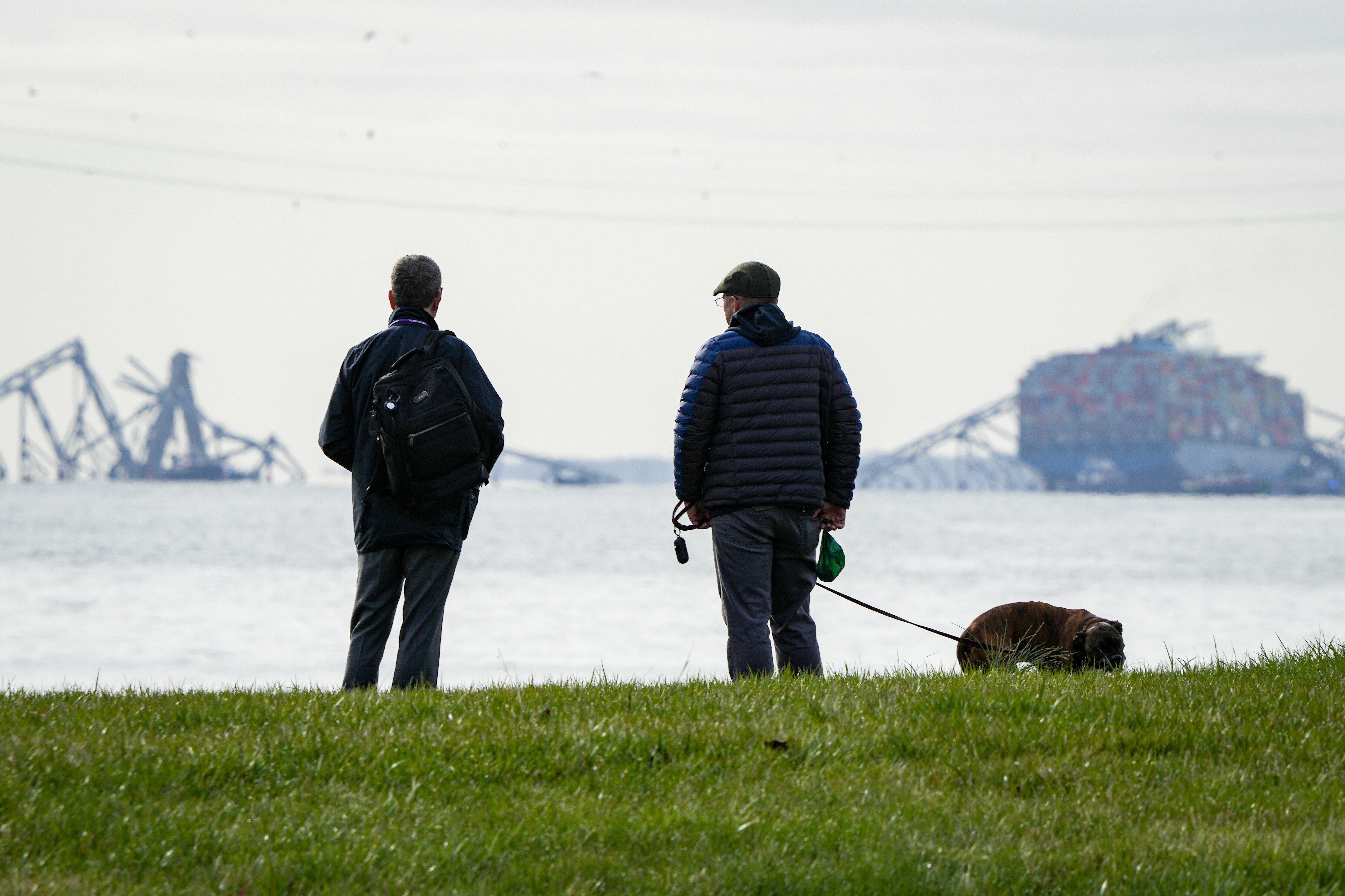 Two men observe the collapsed Francis Scott Key Bridge wreckage from Fort McHenry on March 26.