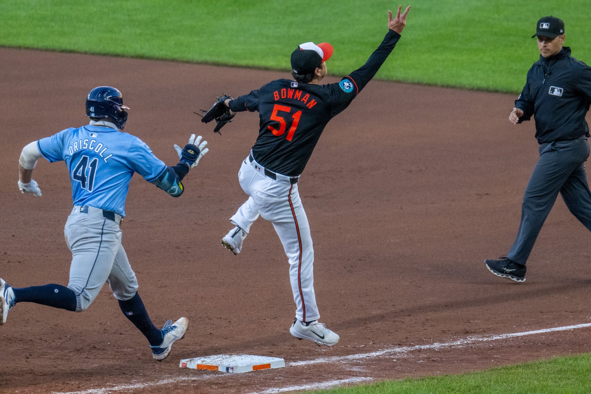 Baltimore Orioles pitcher Matt Bowman leaps for an overthrown ball as Tampa Bay Rays’ Logan Driscoll reaches first in the 7th inning, Saturday, Sept. 7, 2024, at Oriole Park. Rays' Yandy Díaz and Jonathan Aranda scored on the throwing error.