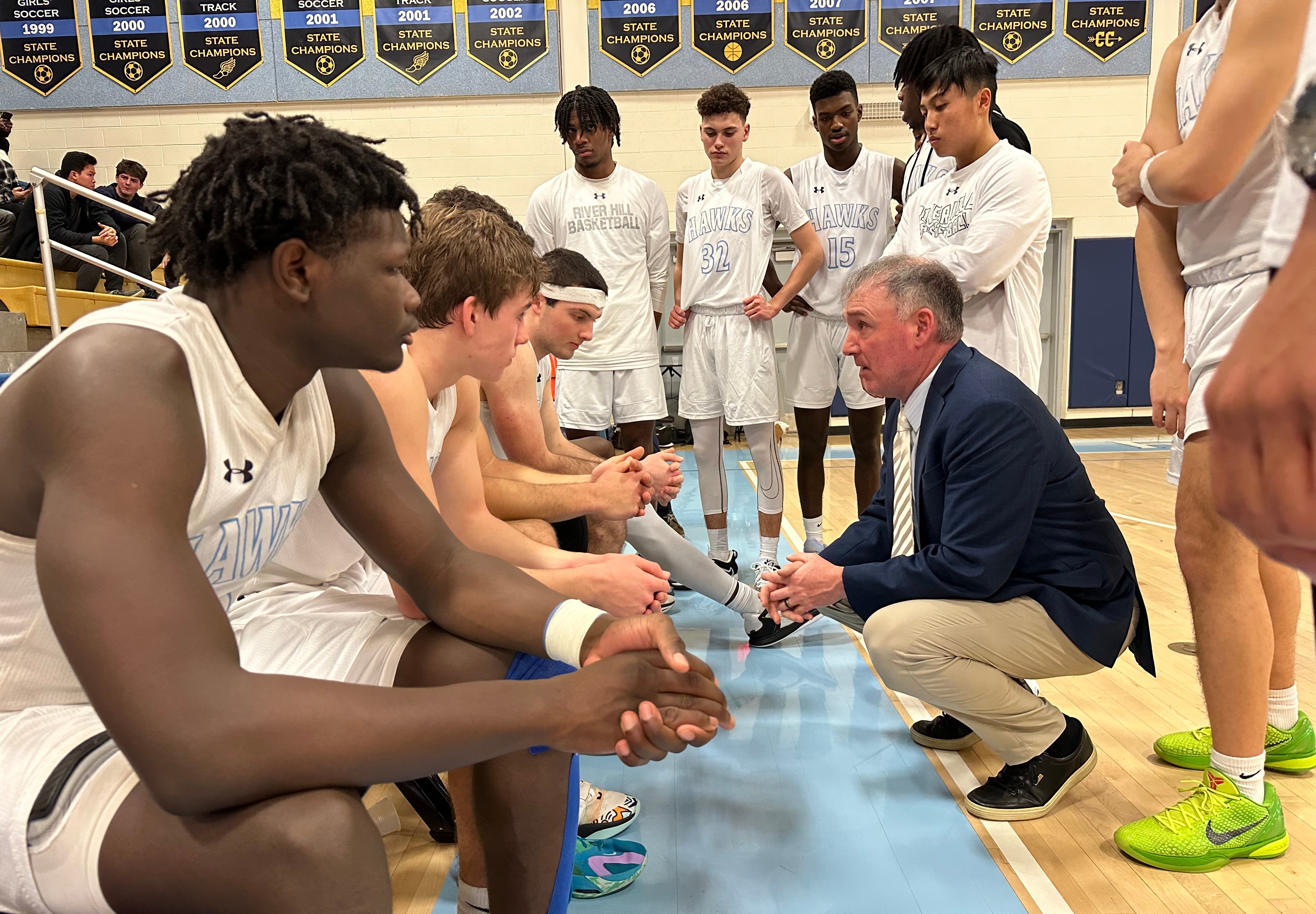 River Hill boys basketball coach Matt Graves (kneeling) talks to his team during Friday night's Howard County contest against Long Reach. The Hawks handed the No. 11 Lightning their first loss, 65-64, in Clarksville.