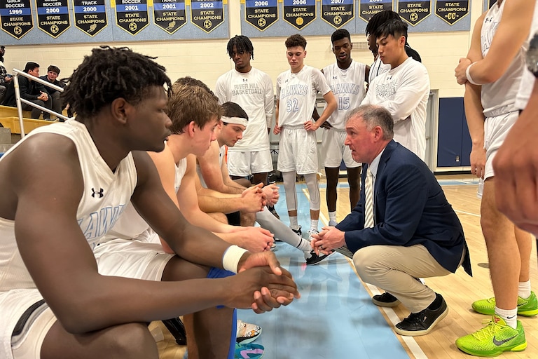 River Hill boys basketball coach Matt Graves (kneeling) talks to his team during Friday night's Howard County contest against Long Reach. The Hawks handed the No. 11 Lightning their first loss, 65-64, in Clarksville.