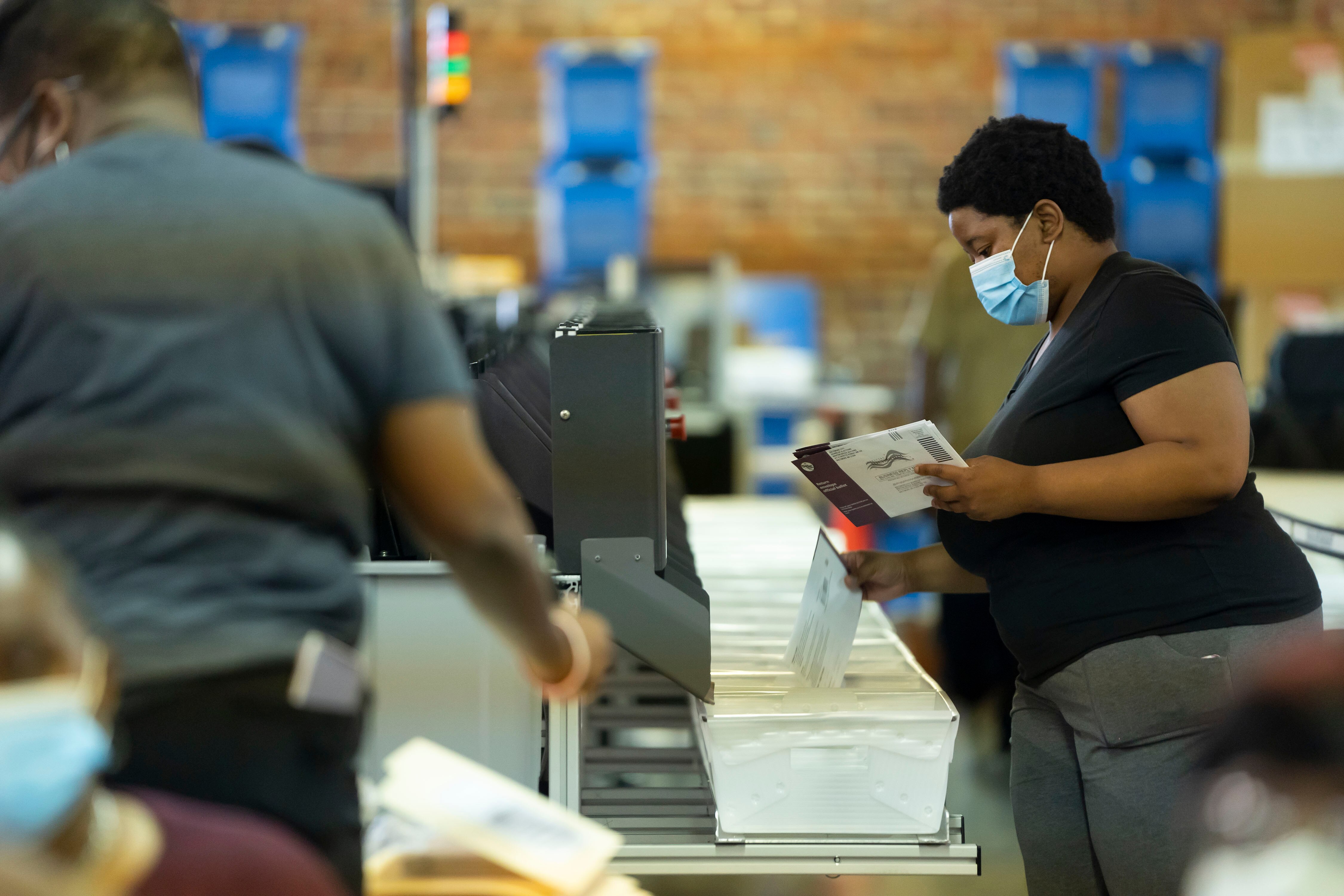 The ballot counters sort through the mail-in ballots using a large machine.